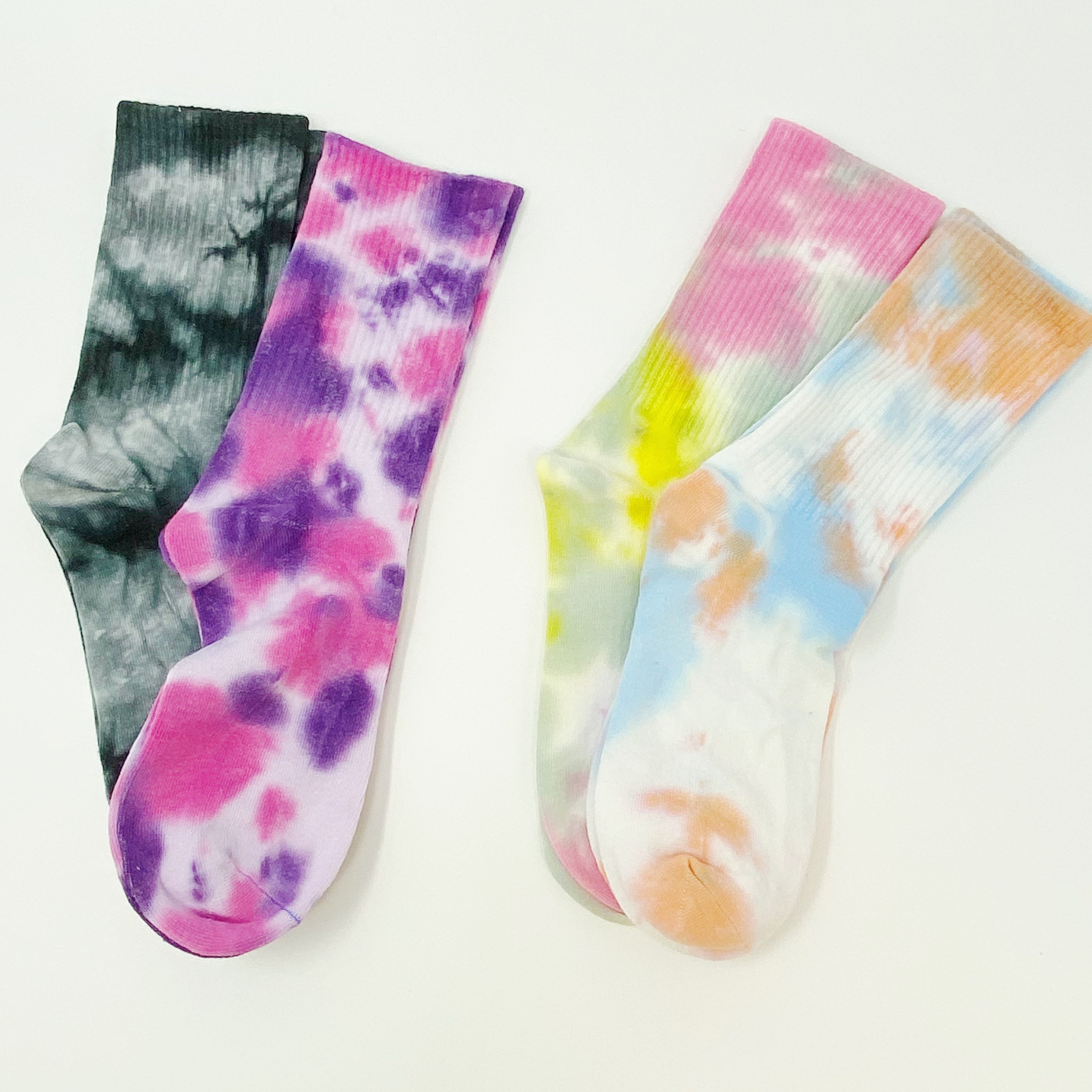 A set of two pairs of colorful tie dye socks, showcasing vibrant patterns and a comfortable fit, packaged in a clear cello bag.