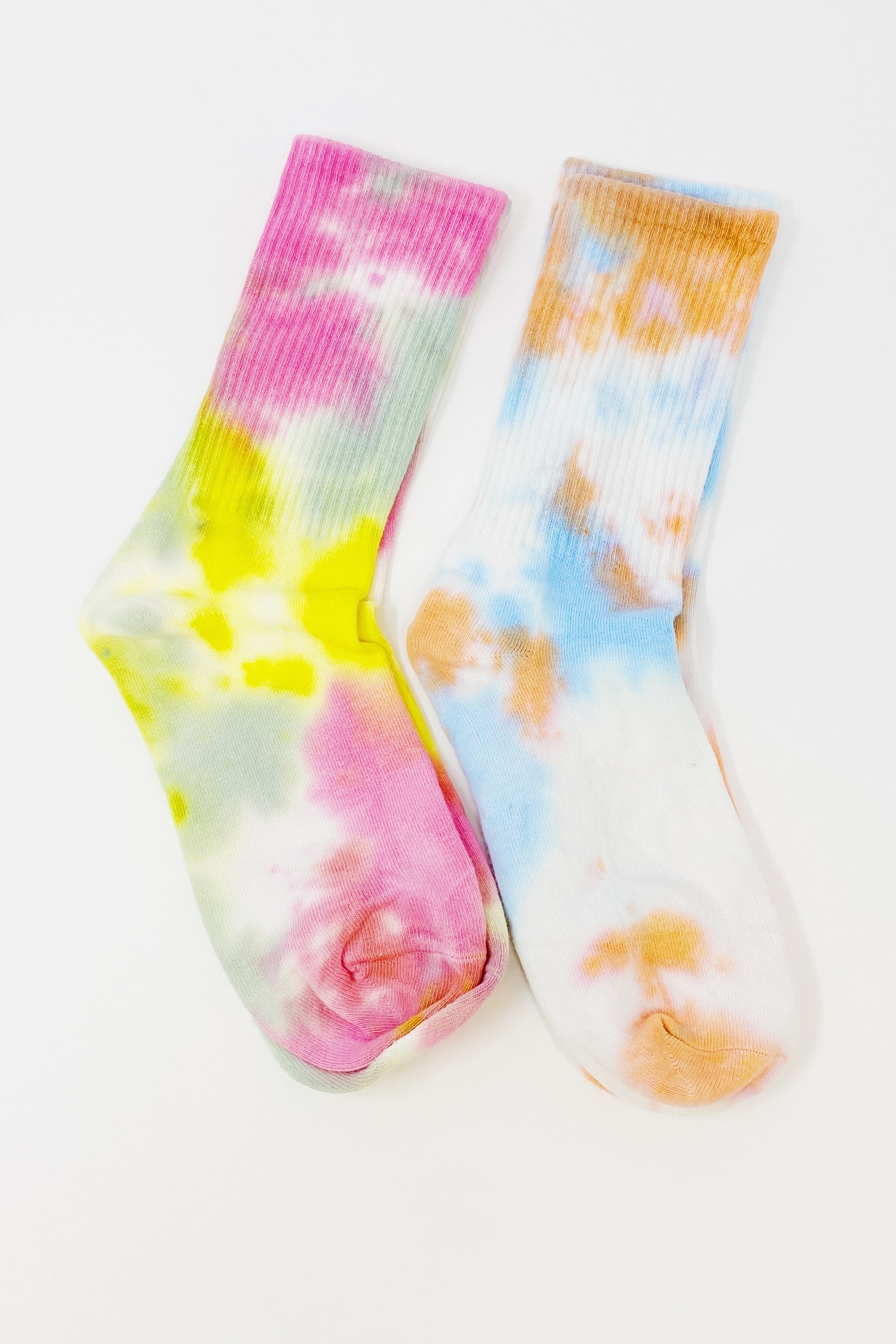 A set of two pairs of colorful tie dye socks, showcasing vibrant patterns and a comfortable fit, packaged in a clear cello bag.