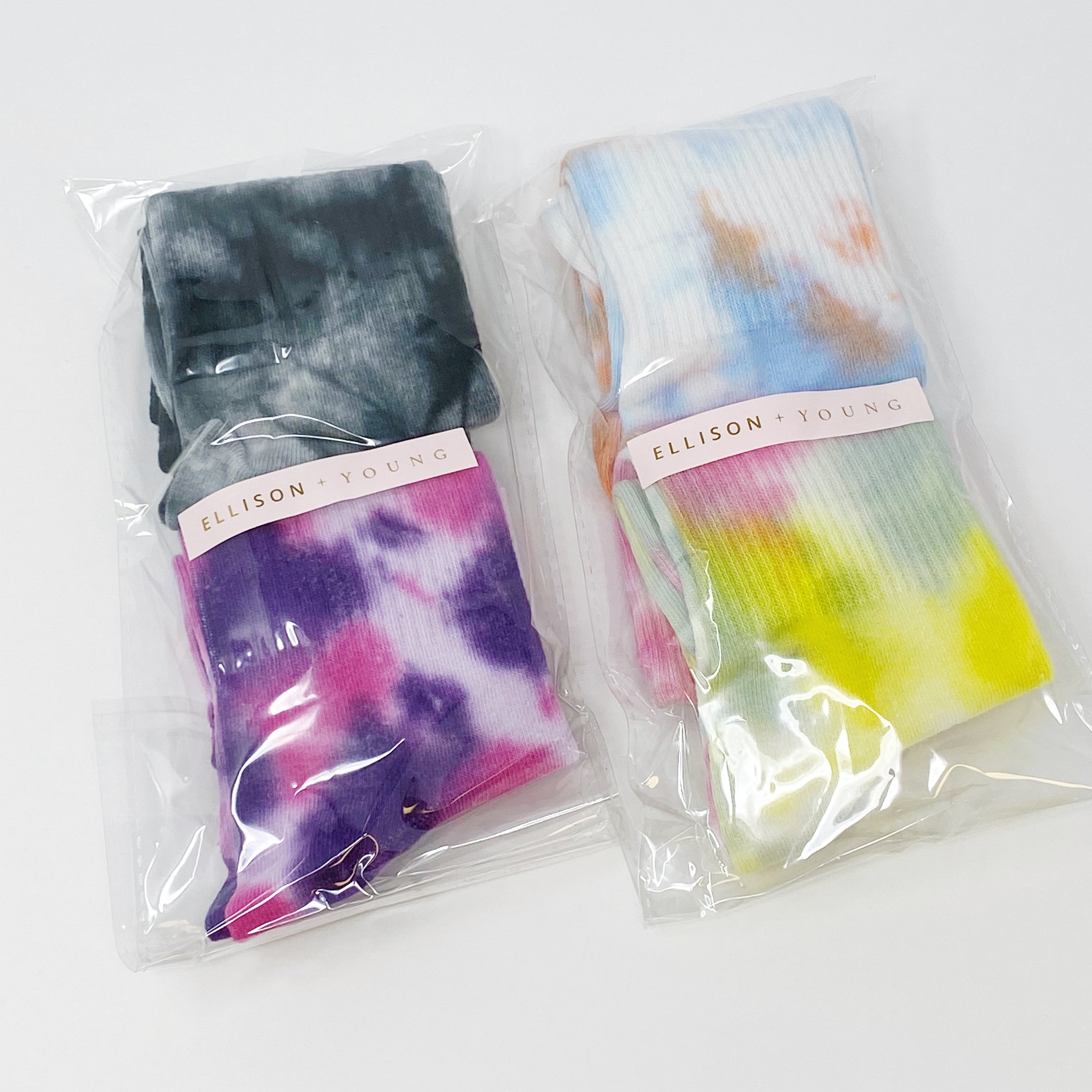 A set of two pairs of colorful tie dye socks, showcasing vibrant patterns and a comfortable fit, packaged in a clear cello bag.