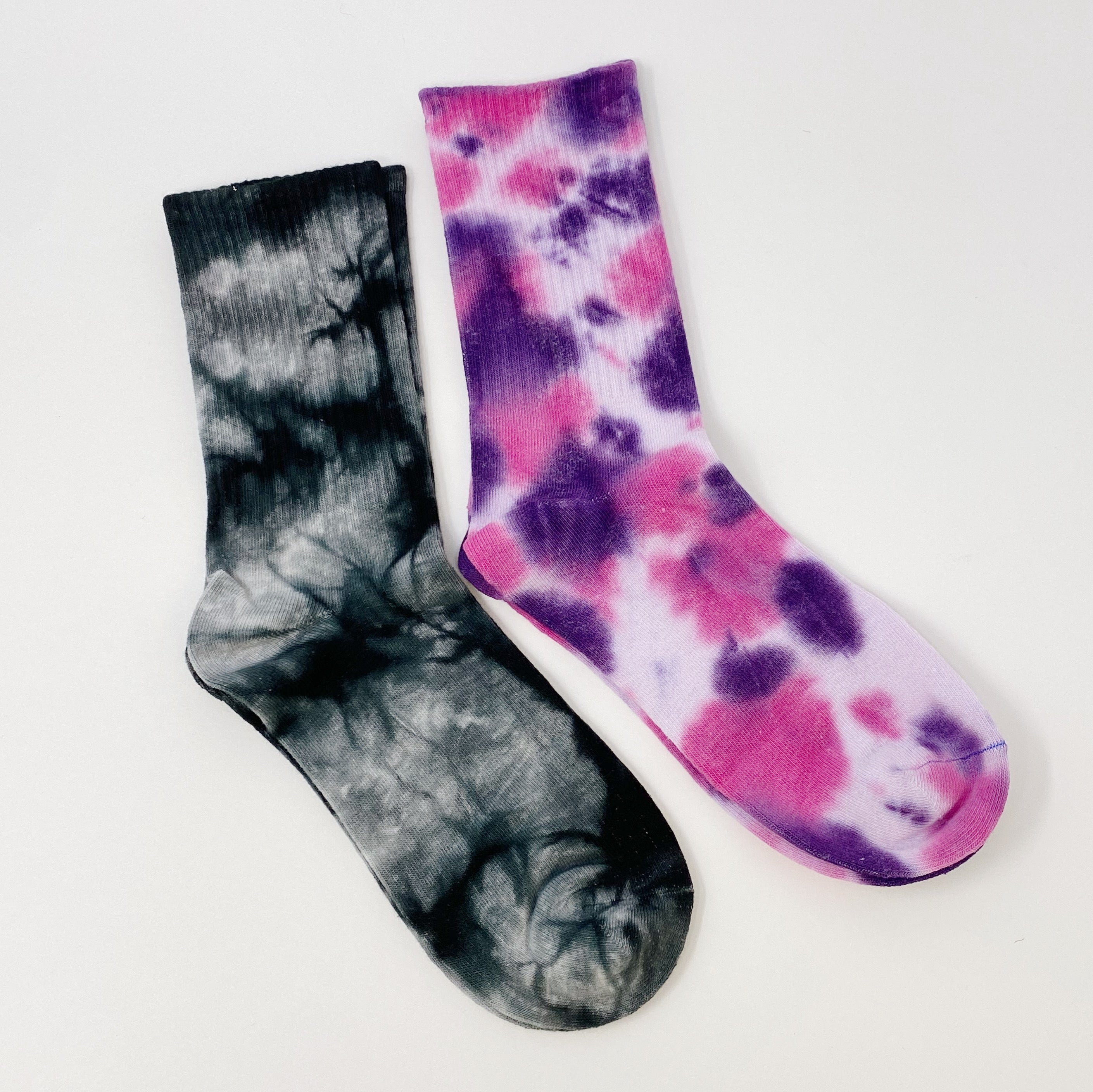 A set of two pairs of colorful tie dye socks, showcasing vibrant patterns and a comfortable fit, packaged in a clear cello bag.