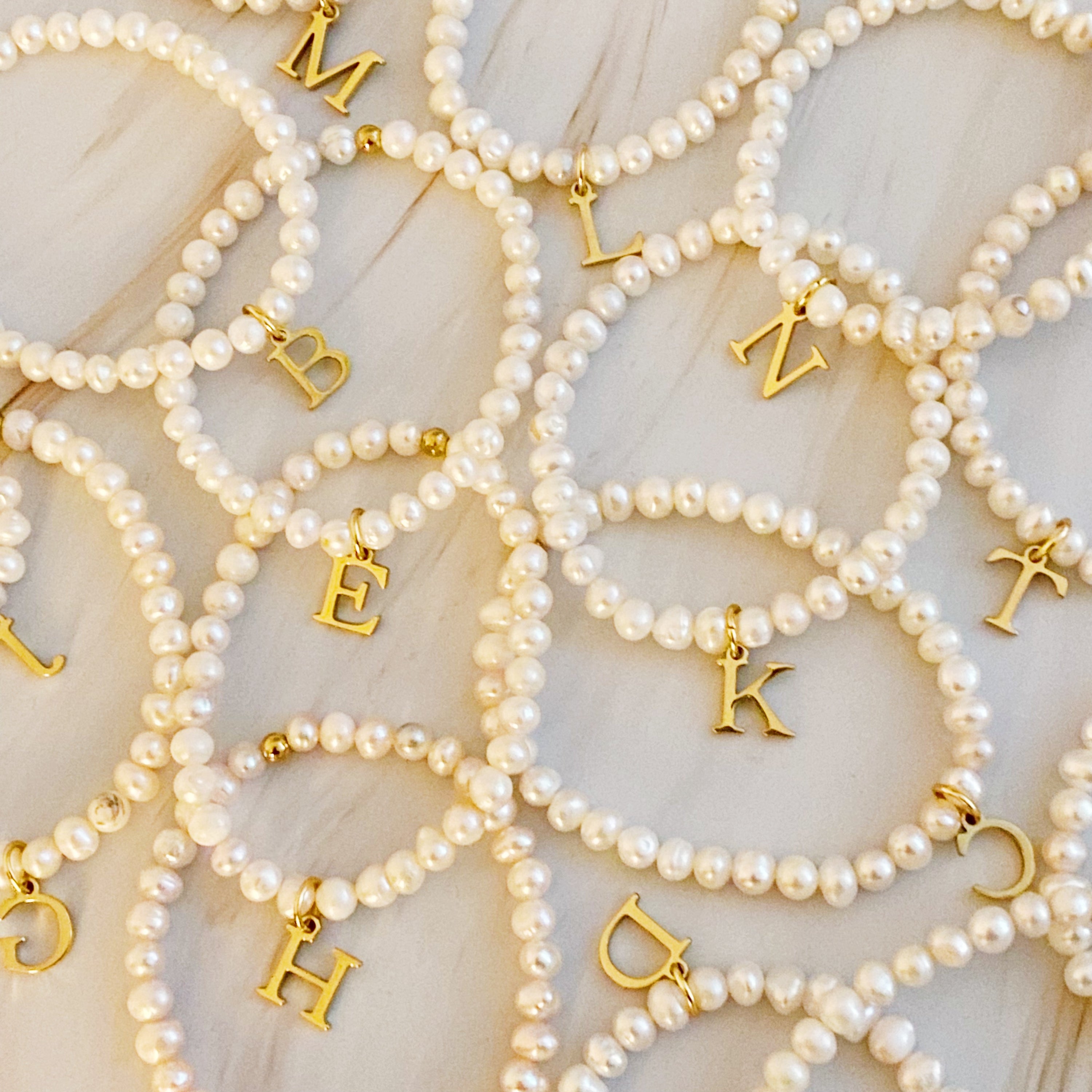 A stylish Freshwater Pearl Initial Charm Bracelet featuring genuine pearls and an 18k gold plated initial charm, perfect for personalized elegance.