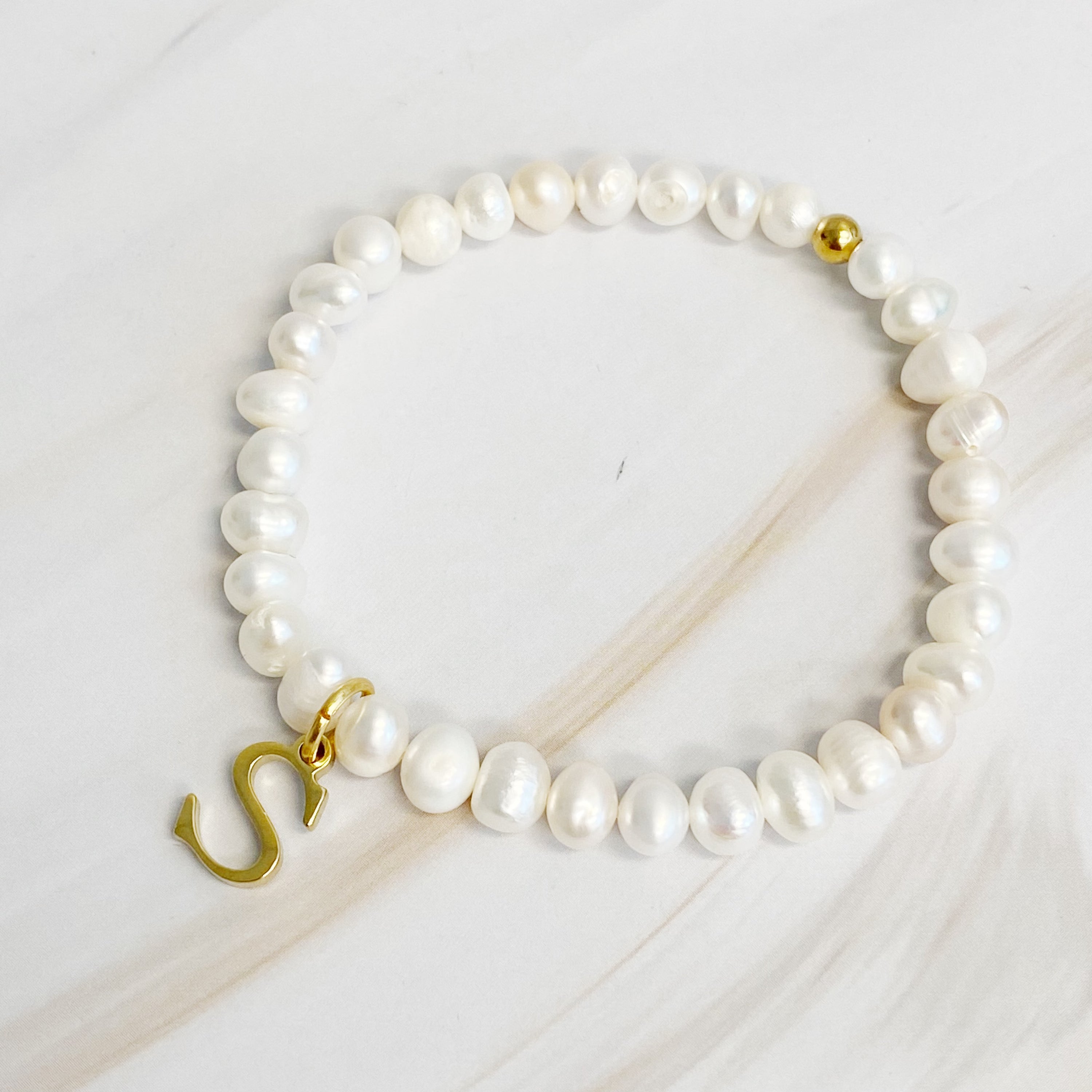 A stylish Freshwater Pearl Initial Charm Bracelet featuring genuine pearls and an 18k gold plated initial charm, perfect for personalized elegance.