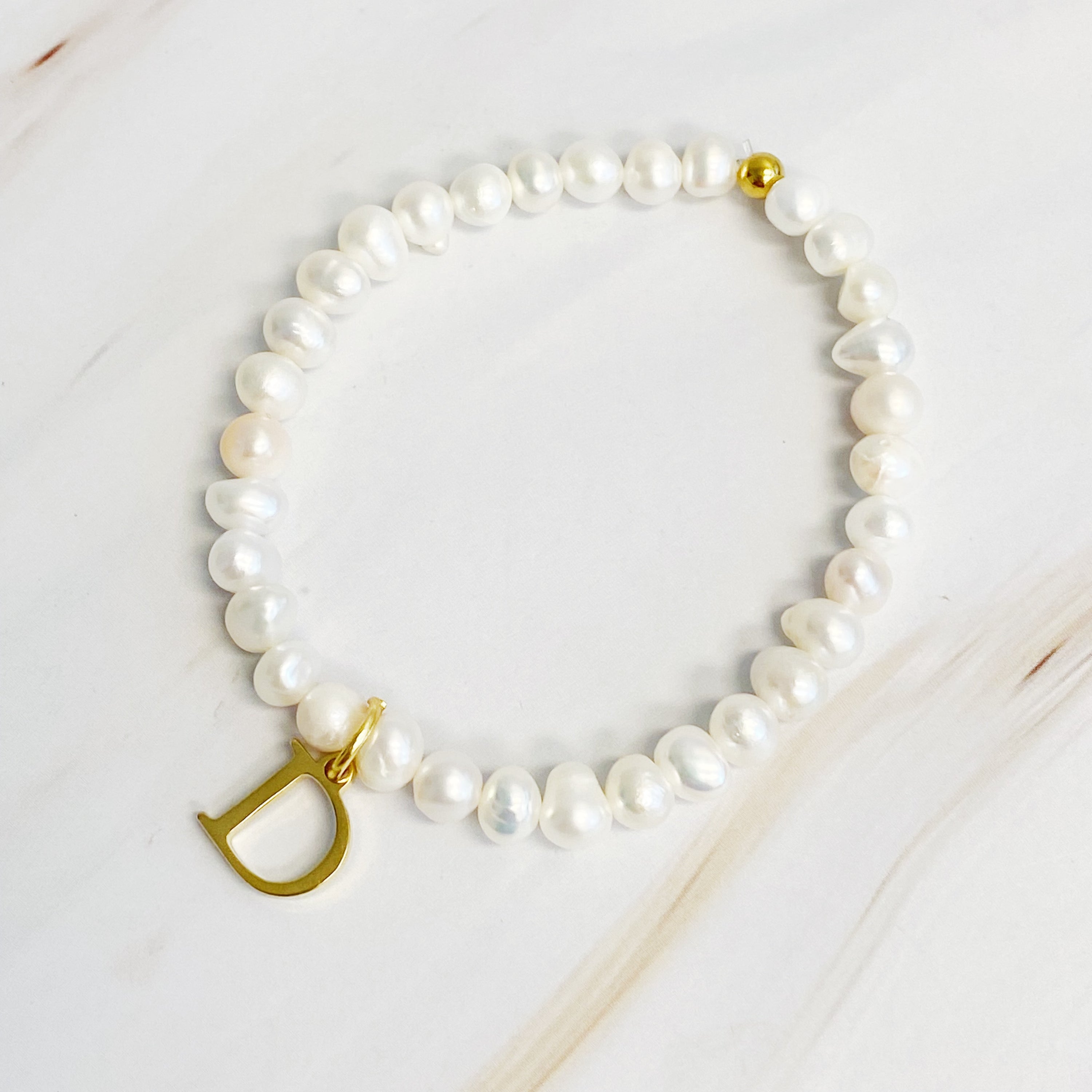 A stylish Freshwater Pearl Initial Charm Bracelet featuring genuine pearls and an 18k gold plated initial charm, perfect for personalized elegance.