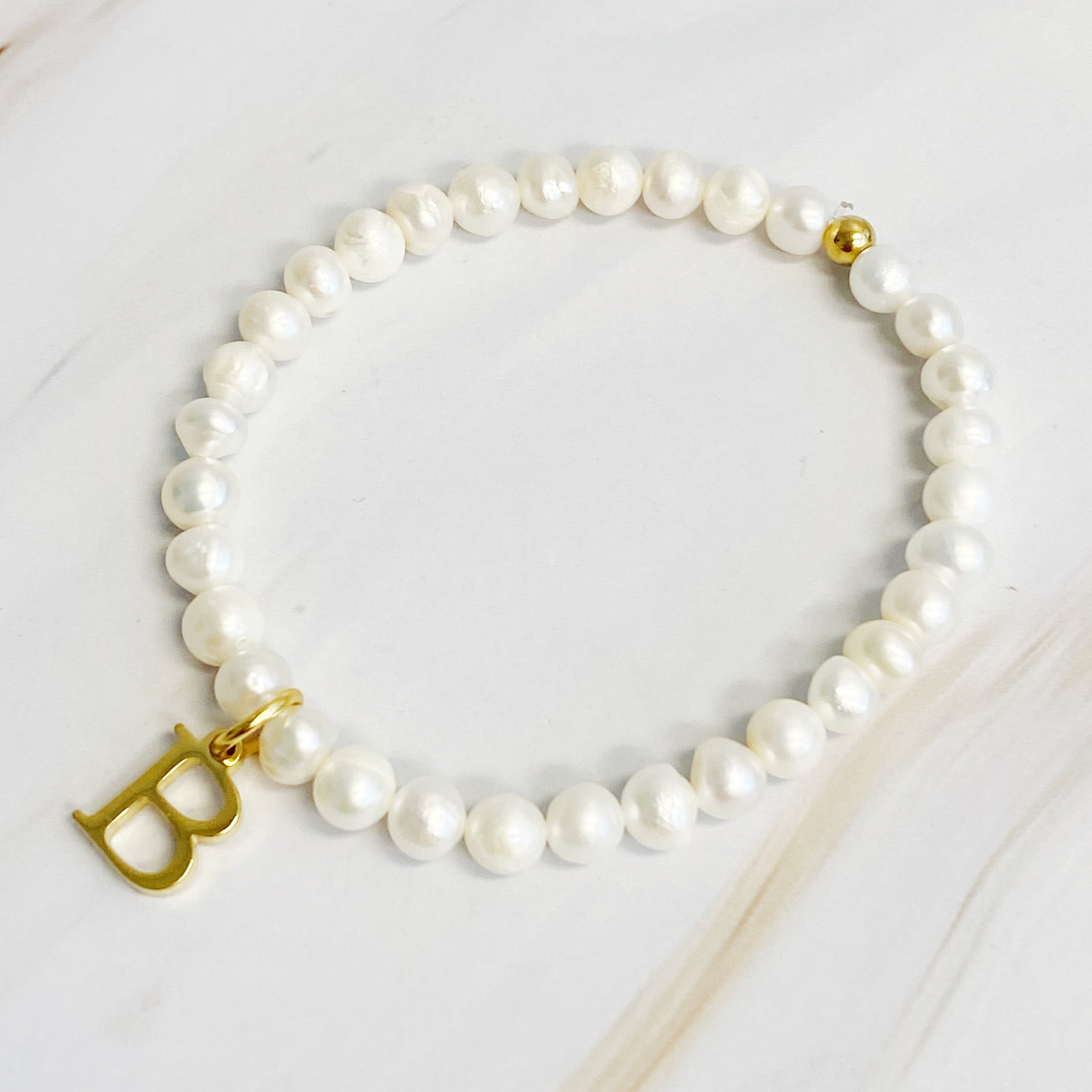 A stylish Freshwater Pearl Initial Charm Bracelet featuring genuine pearls and an 18k gold plated initial charm, perfect for personalized elegance.