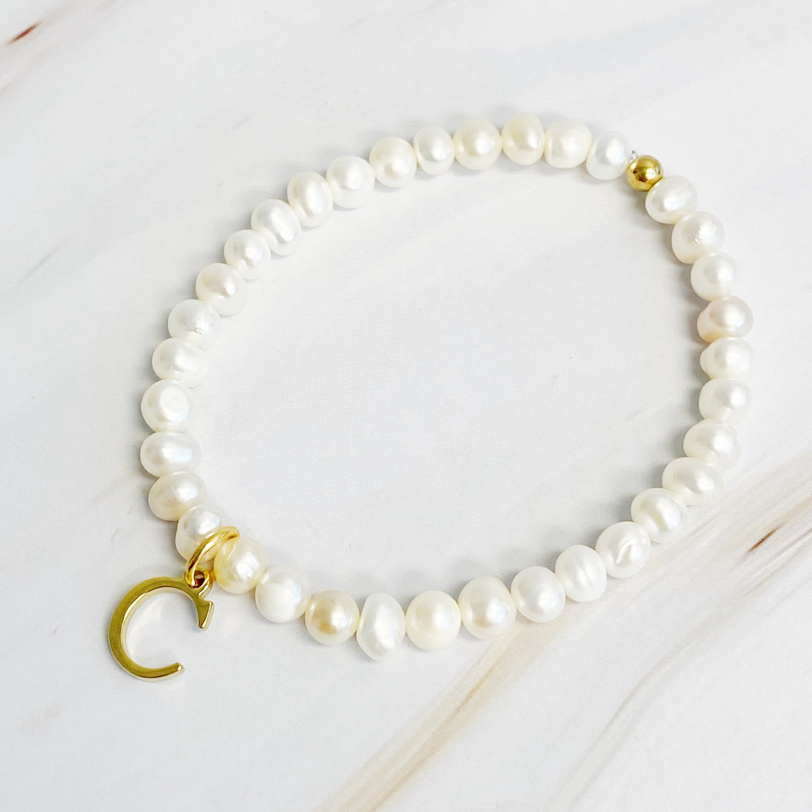 A stylish Freshwater Pearl Initial Charm Bracelet featuring genuine pearls and an 18k gold plated initial charm, perfect for personalized elegance.