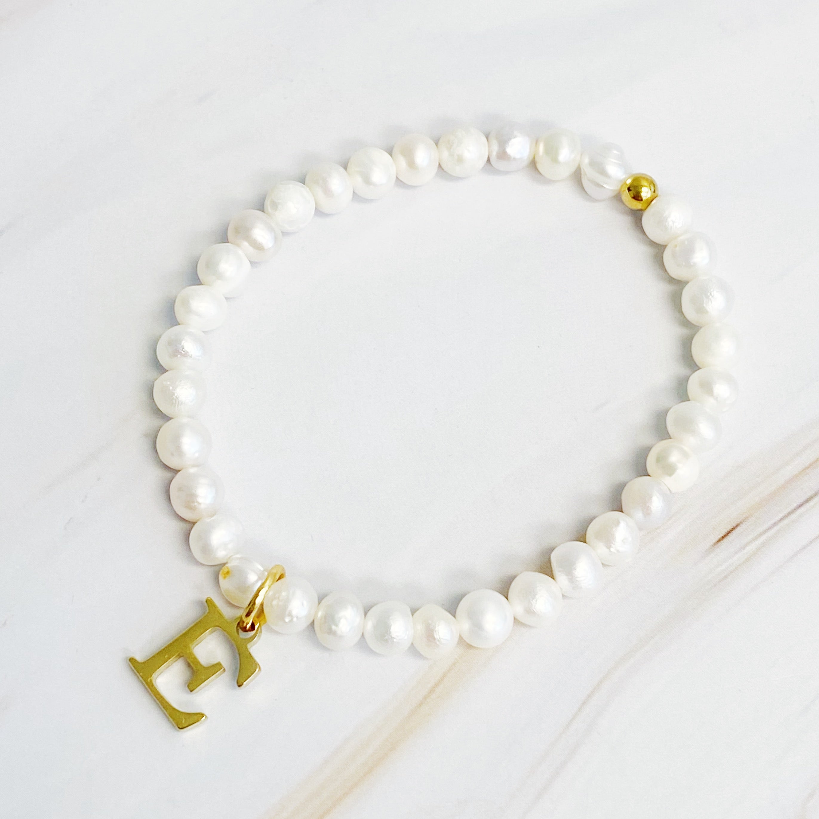 A stylish Freshwater Pearl Initial Charm Bracelet featuring genuine pearls and an 18k gold plated initial charm, perfect for personalized elegance.