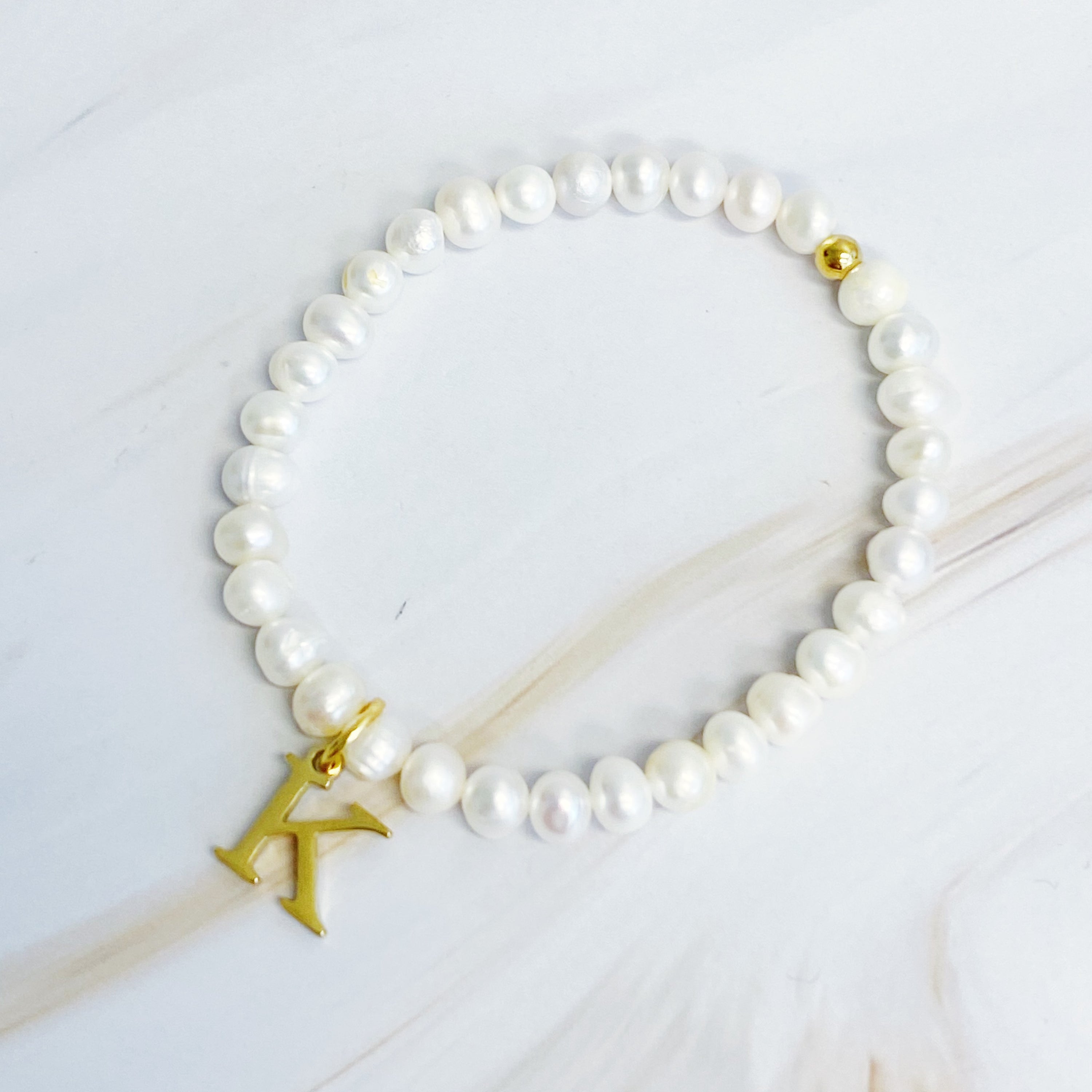 A stylish Freshwater Pearl Initial Charm Bracelet featuring genuine pearls and an 18k gold plated initial charm, perfect for personalized elegance.