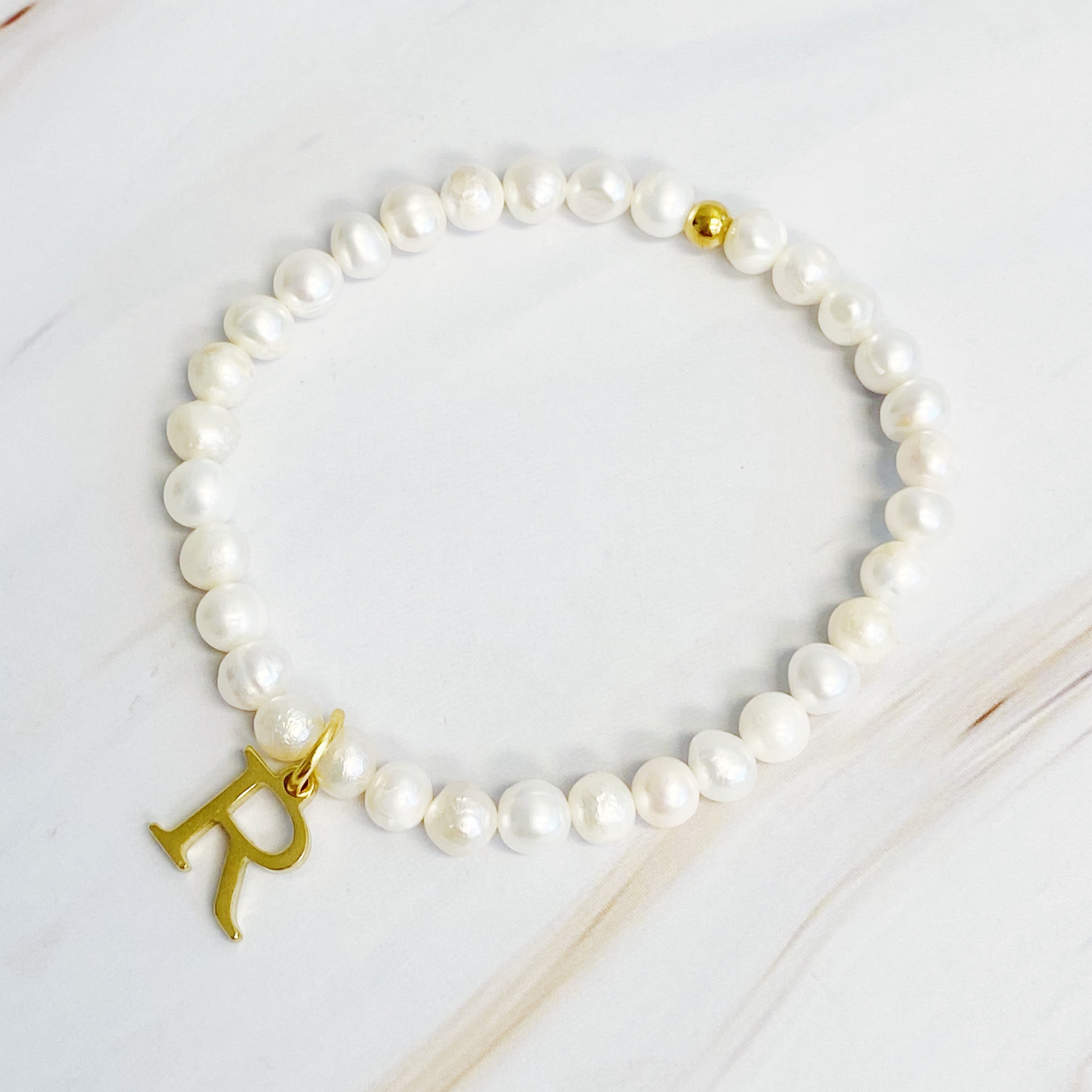 A stylish Freshwater Pearl Initial Charm Bracelet featuring genuine pearls and an 18k gold plated initial charm, perfect for personalized elegance.