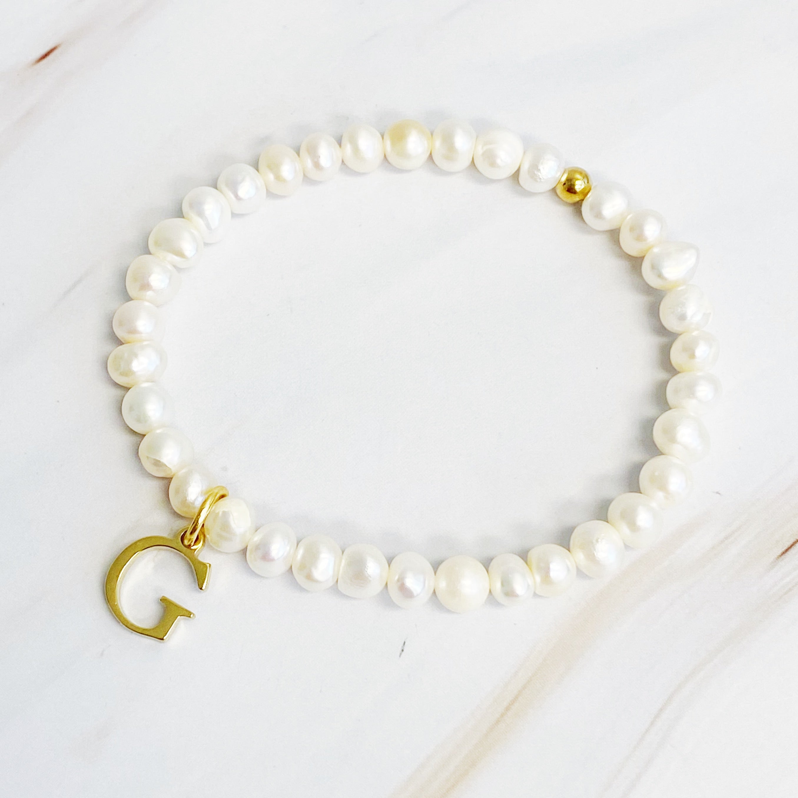 A stylish Freshwater Pearl Initial Charm Bracelet featuring genuine pearls and an 18k gold plated initial charm, perfect for personalized elegance.