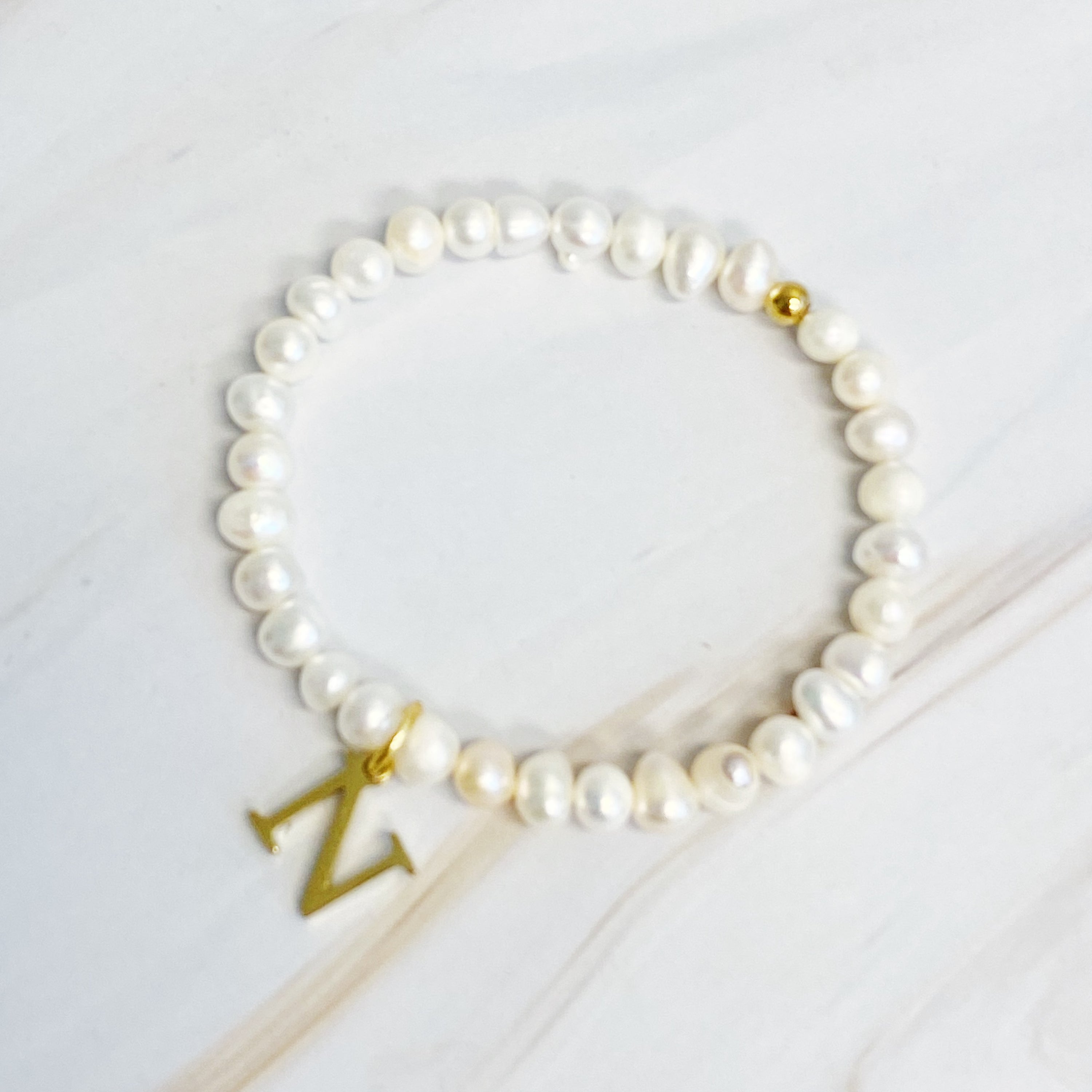 A stylish Freshwater Pearl Initial Charm Bracelet featuring genuine pearls and an 18k gold plated initial charm, perfect for personalized elegance.