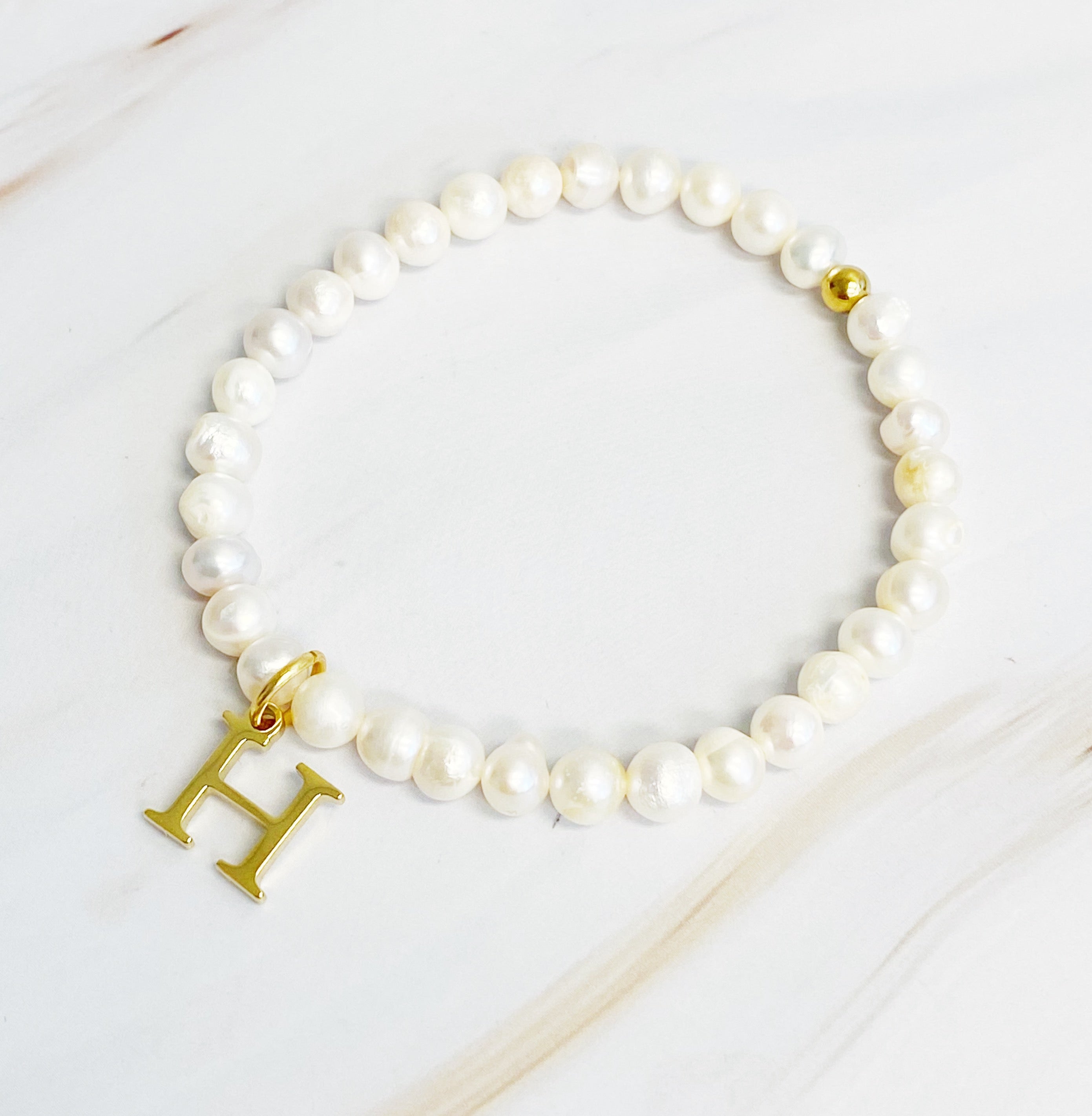 A stylish Freshwater Pearl Initial Charm Bracelet featuring genuine pearls and an 18k gold plated initial charm, perfect for personalized elegance.