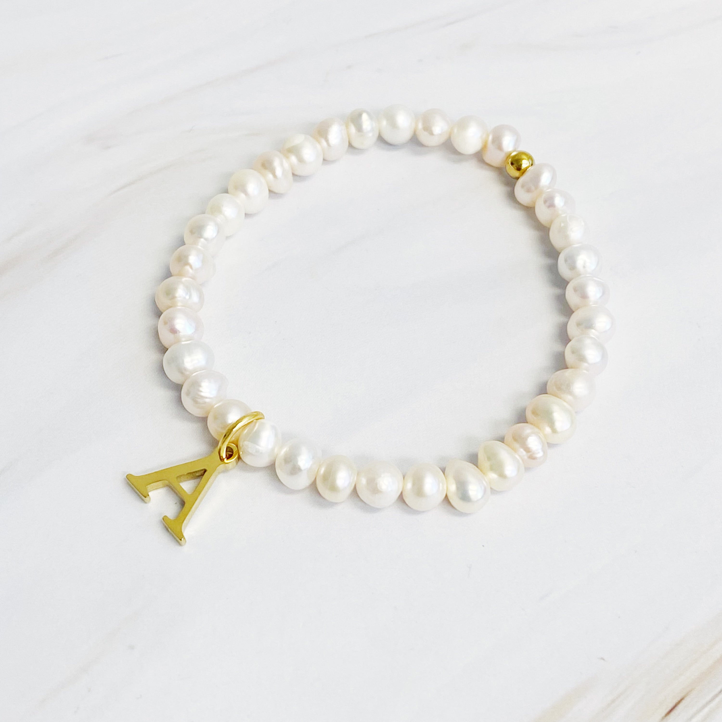 A stylish Freshwater Pearl Initial Charm Bracelet featuring genuine pearls and an 18k gold plated initial charm, perfect for personalized elegance.