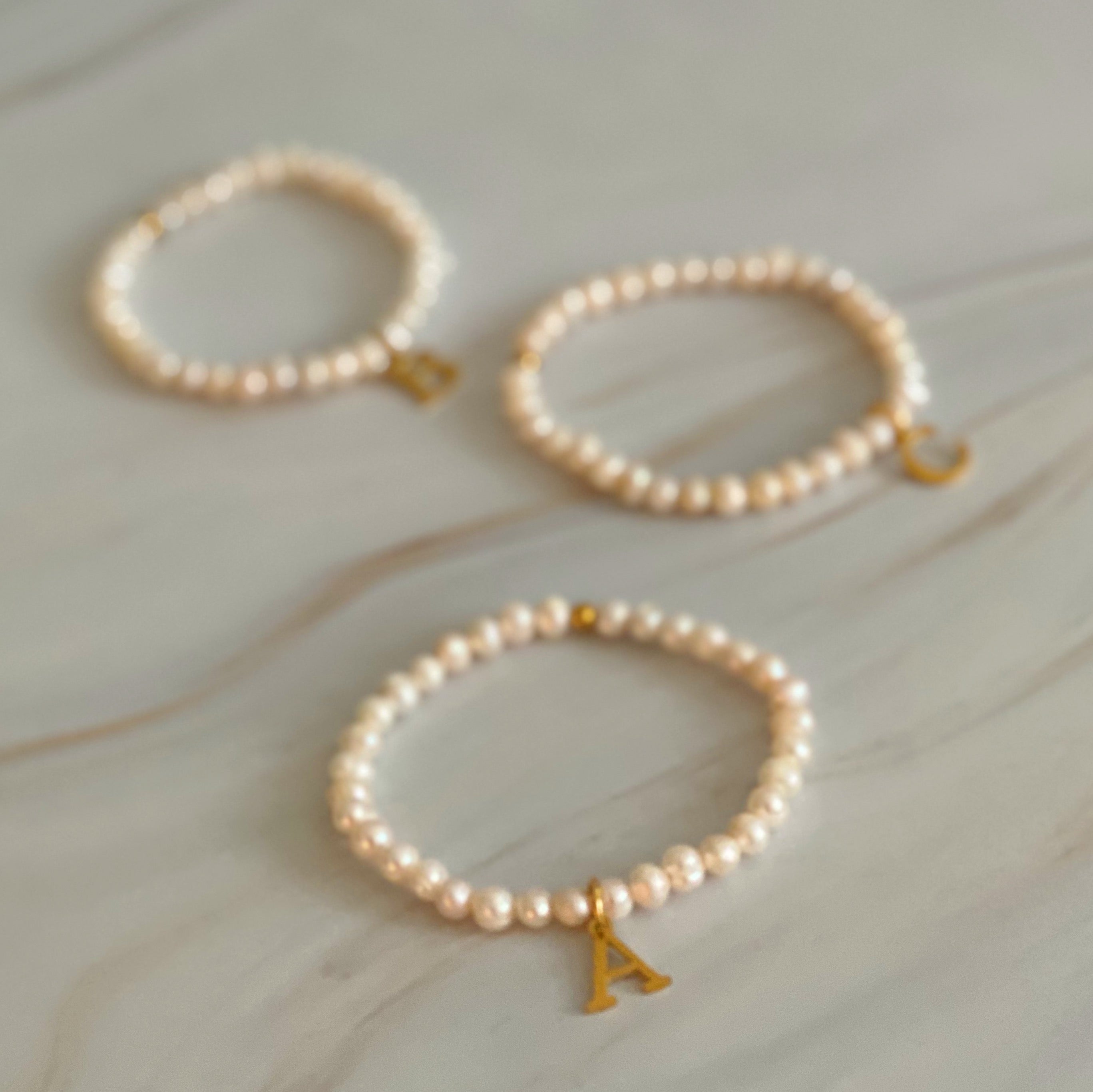 A stylish Freshwater Pearl Initial Charm Bracelet featuring genuine pearls and an 18k gold plated initial charm, perfect for personalized elegance.