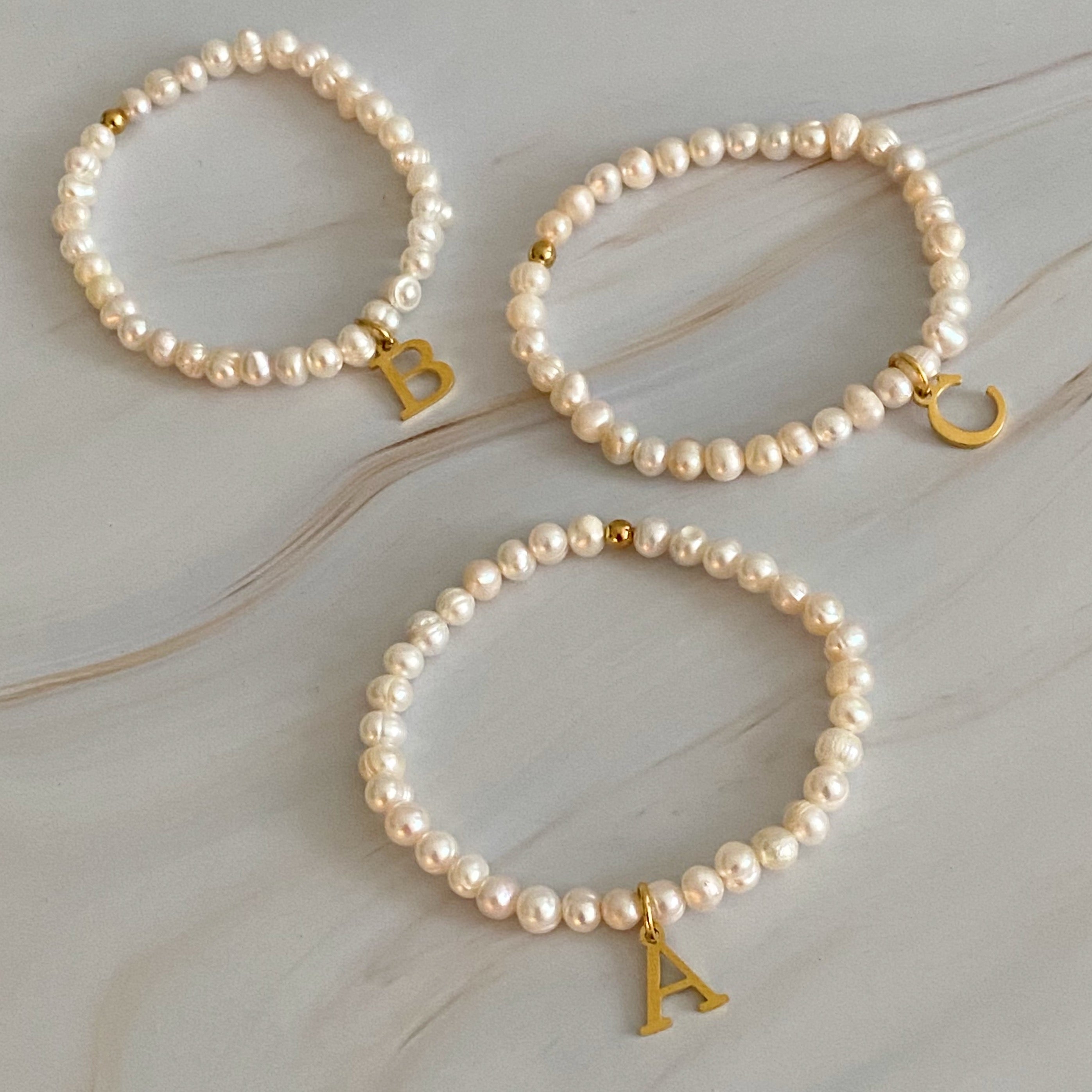 A stylish Freshwater Pearl Initial Charm Bracelet featuring genuine pearls and an 18k gold plated initial charm, perfect for personalized elegance.