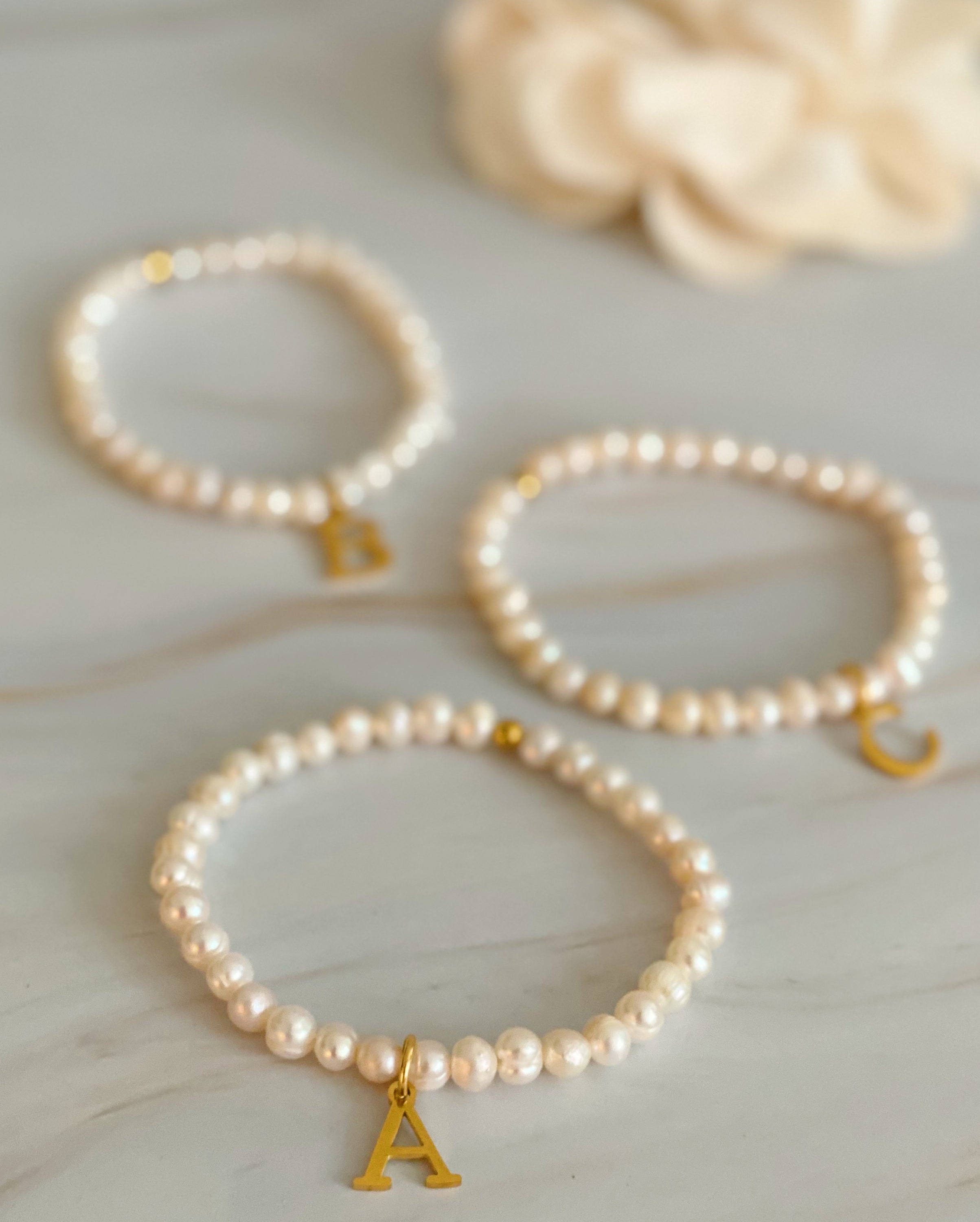 A stylish Freshwater Pearl Initial Charm Bracelet featuring genuine pearls and an 18k gold plated initial charm, perfect for personalized elegance.