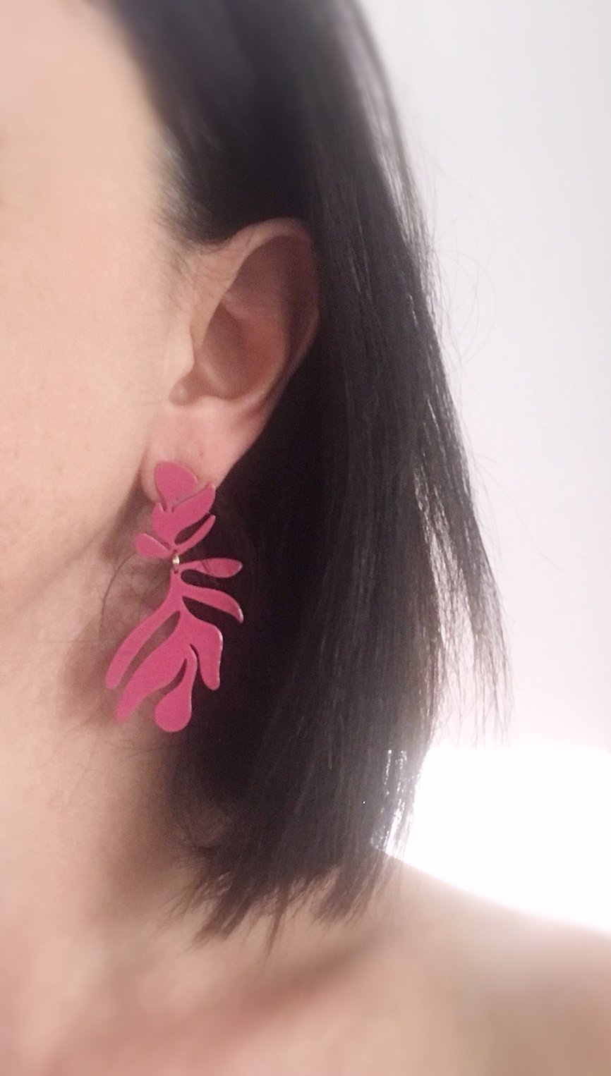 A pair of lightweight floral-inspired frond earrings in brushed brass, showcasing their elegant design and stainless steel ear posts.