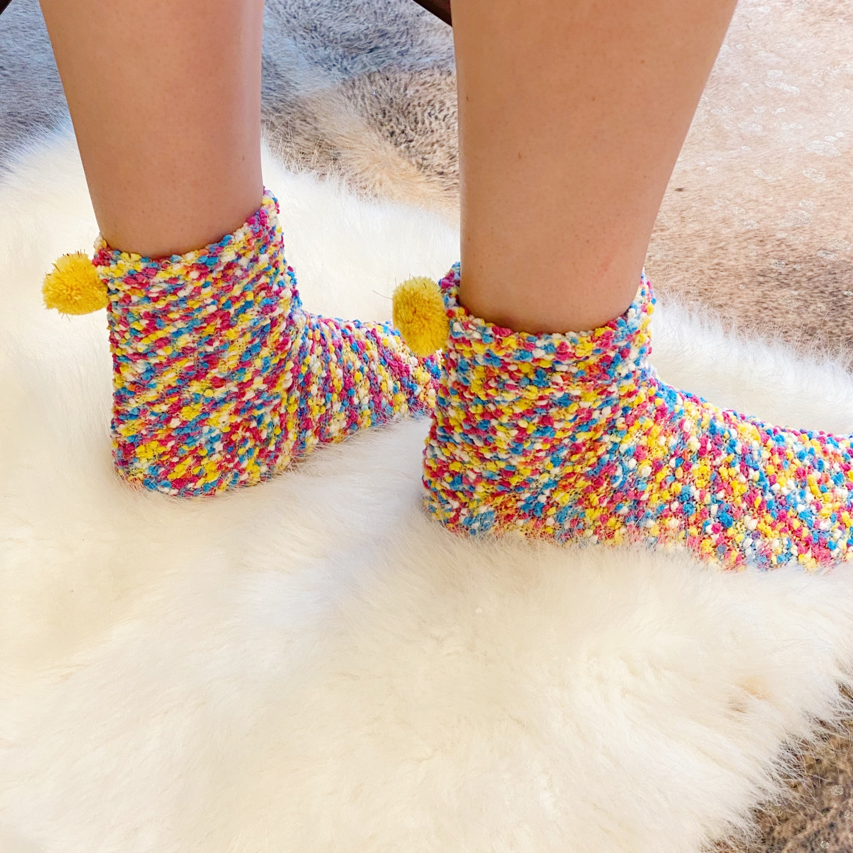 Soft and fuzzy Fuzzy Pom Confetti Socks with a cute pom detail on the back, displayed in cupcake packaging.