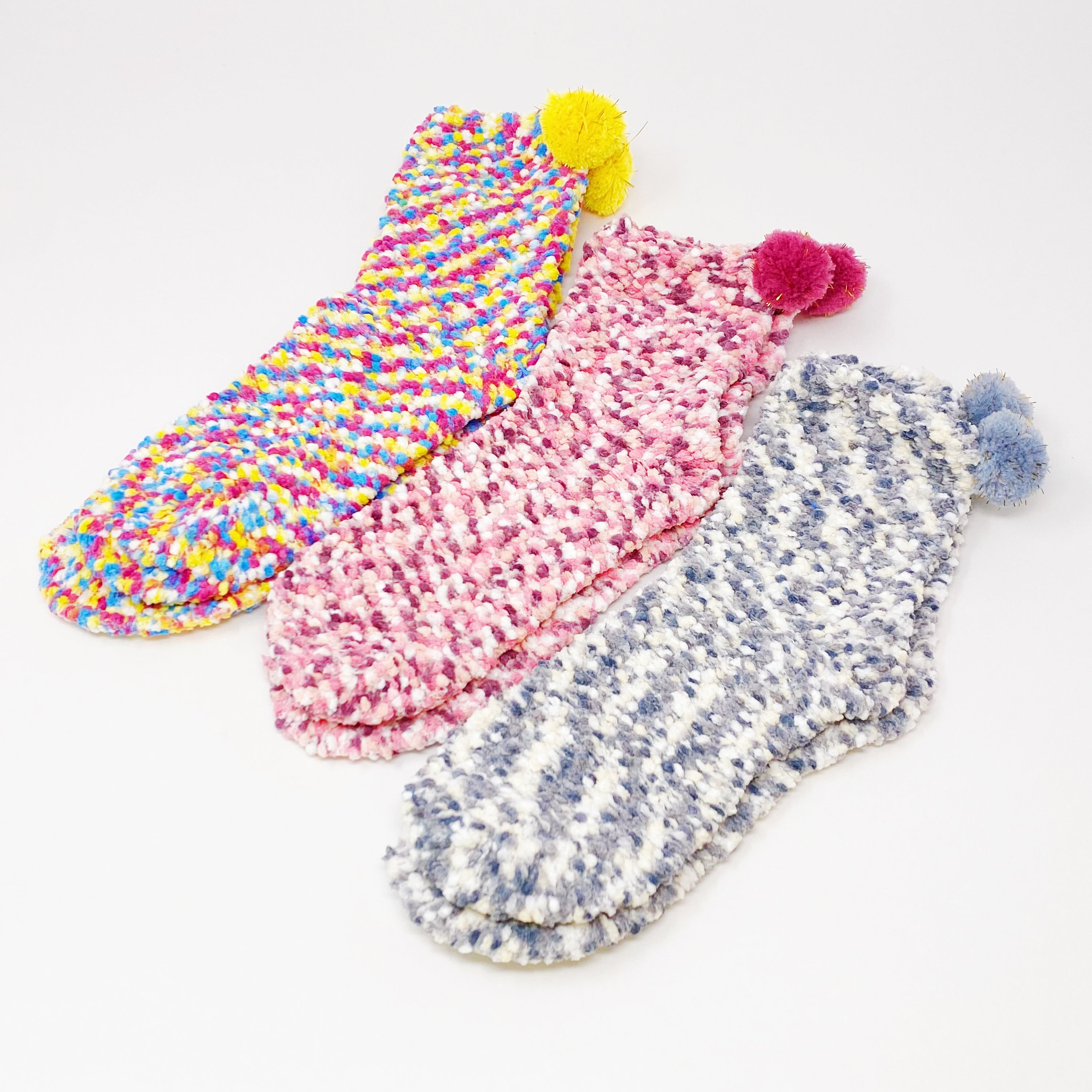 Soft and fuzzy Fuzzy Pom Confetti Socks with a cute pom detail on the back, displayed in cupcake packaging.