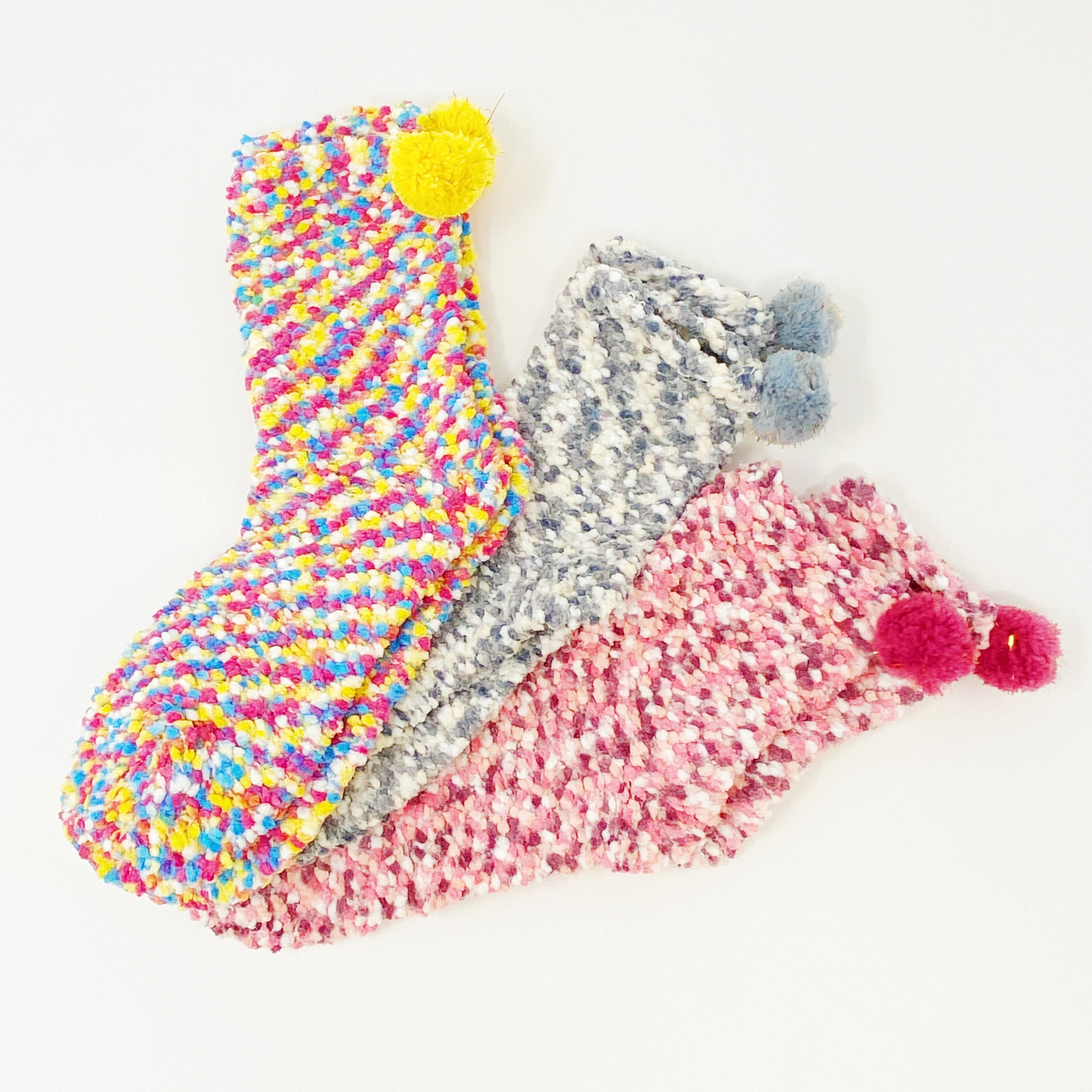 Soft and fuzzy Fuzzy Pom Confetti Socks with a cute pom detail on the back, displayed in cupcake packaging.