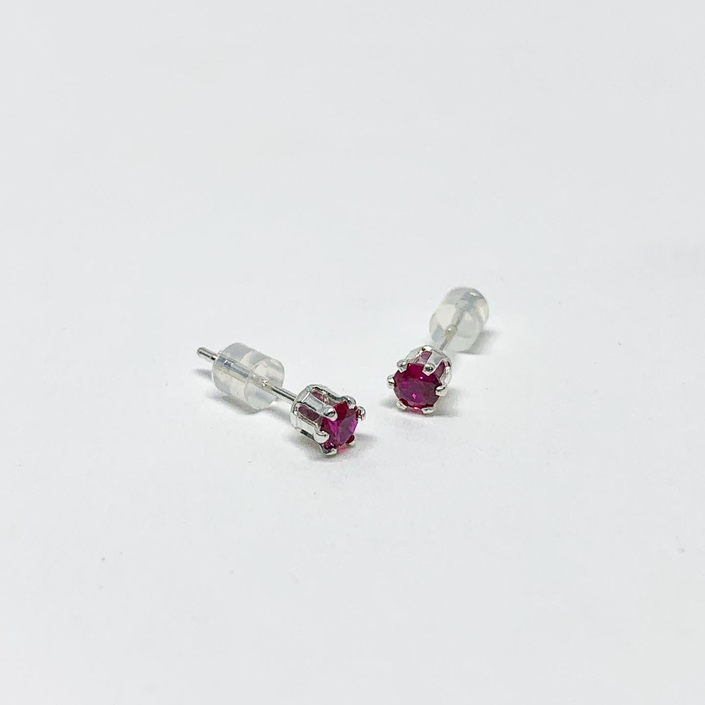 A pair of stunning garnet birthstone earrings featuring 3mm round faceted pink-red garnet gemstones set in sterling silver or yellow gold fill.