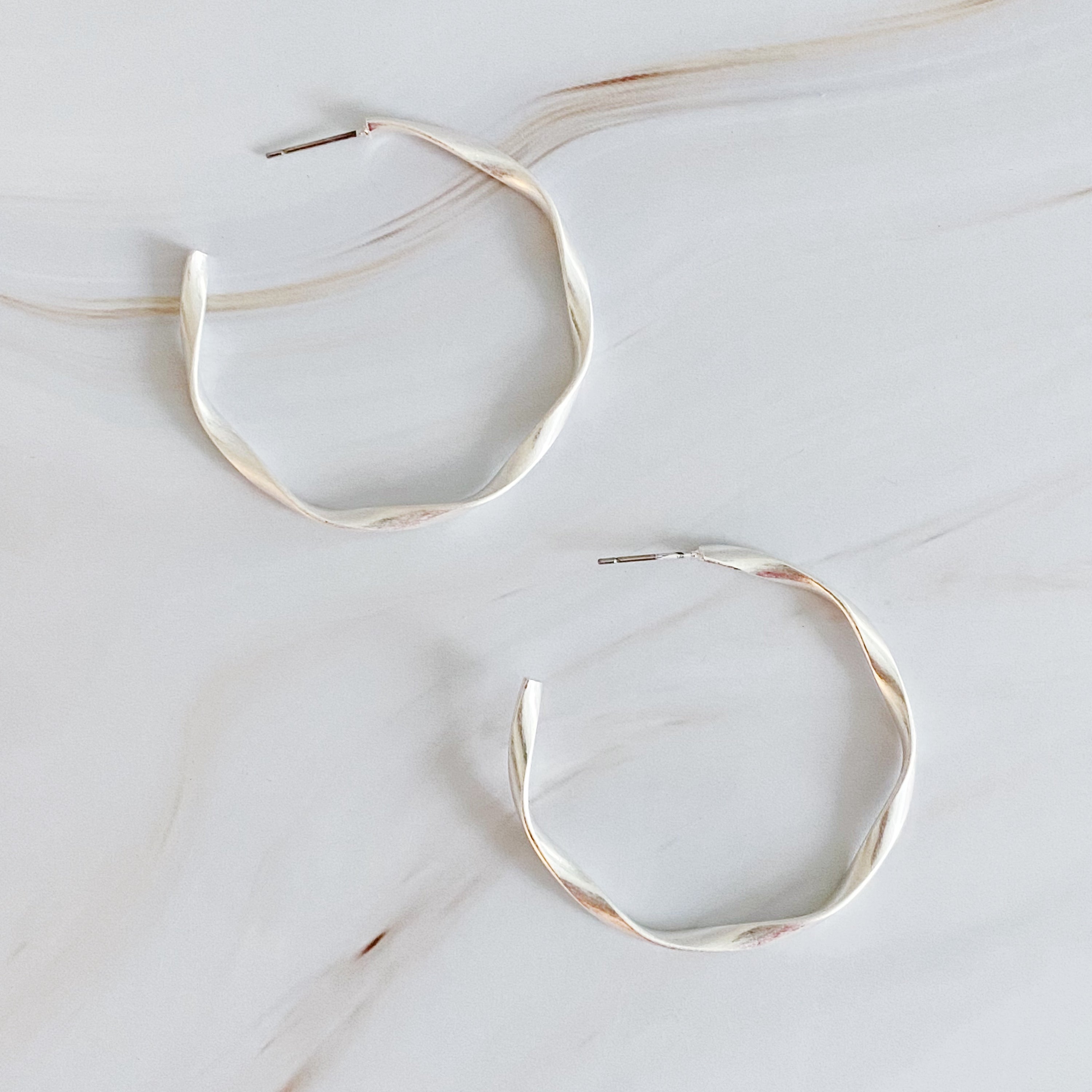 Gentle Wave Sleek Hoop Earrings with a softly twisted design and matte finish, showcasing their elegant and modern style.