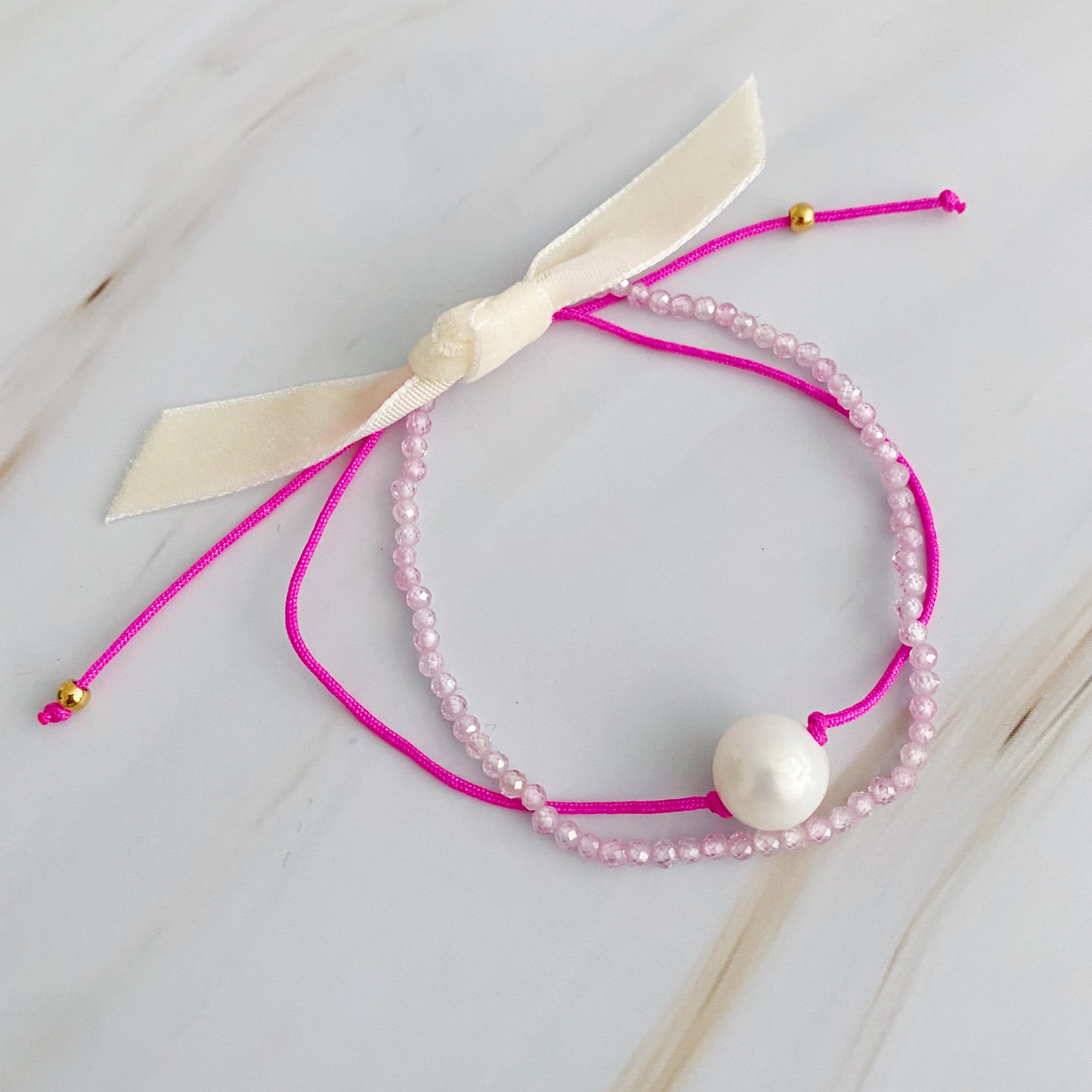 Genuine Pearl Color Dream Bracelet Set of 2 featuring freshwater pearls, colorful threads, and sparkly glass beads, elegantly displayed with a cream velvet bow.