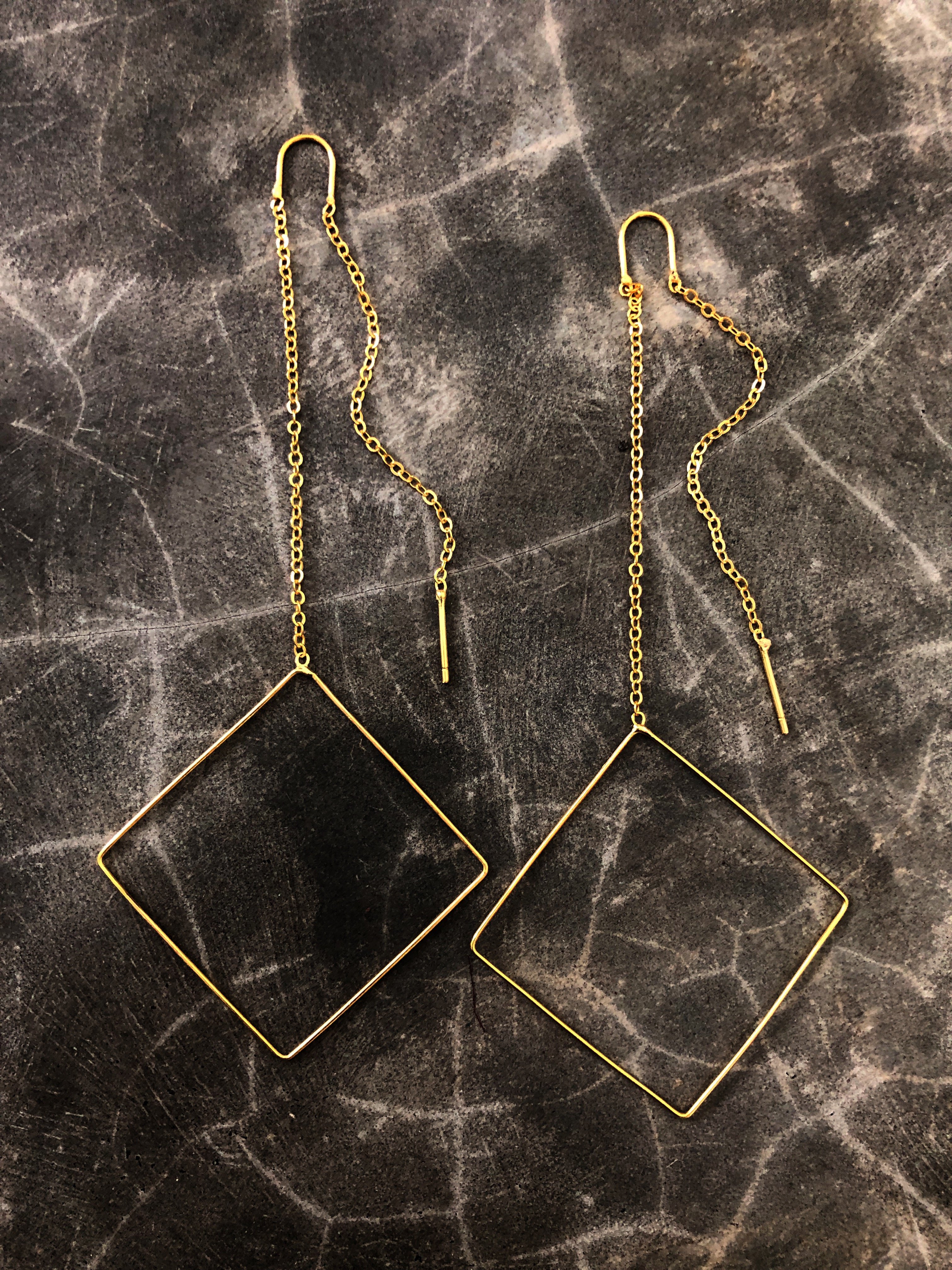 A pair of elegant Geometric Threader Earrings featuring a circle, square, and triangle design, handcrafted with 18K gold plating.