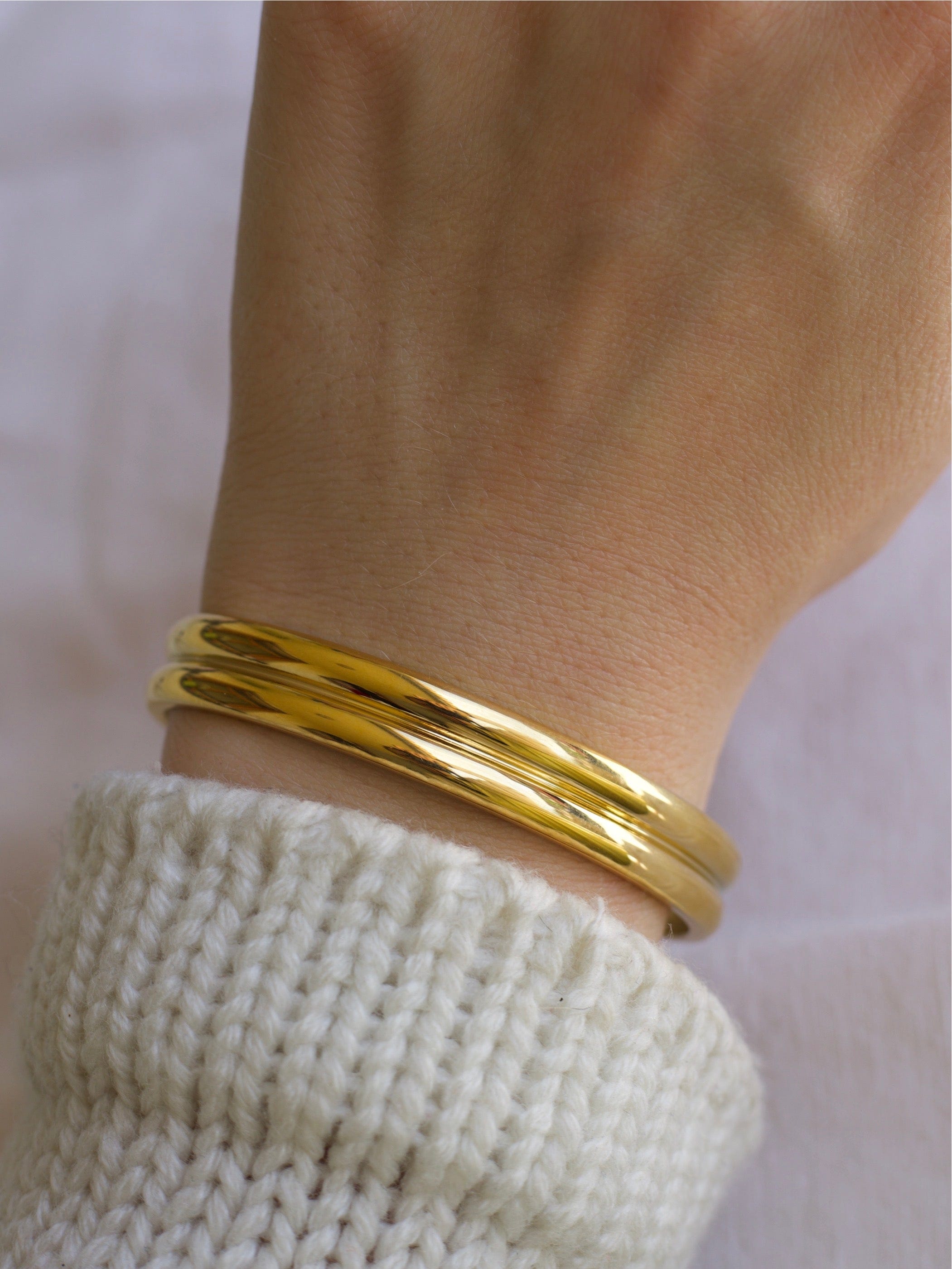 Gil Wide Polished Cuff Bracelet in Gold, showcasing its shiny stainless steel and 18K gold plating with an adjustable open cuff design.