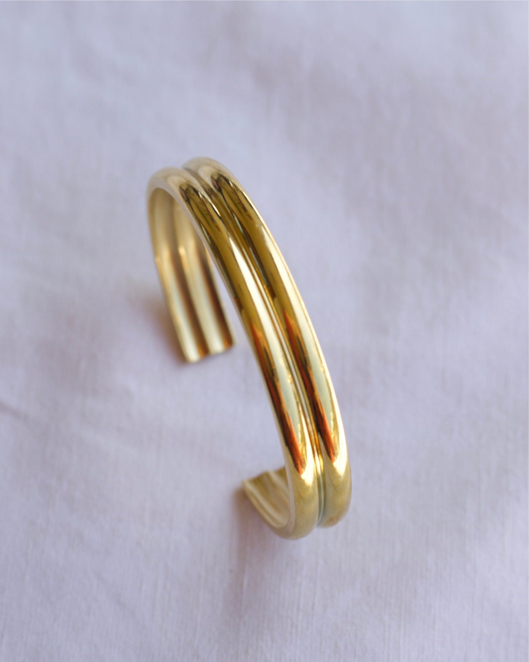 Gil Wide Polished Cuff Bracelet in Gold, showcasing its shiny stainless steel and 18K gold plating with an adjustable open cuff design.