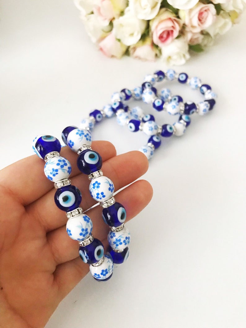 A beautiful Glass Evil Eye Bracelet featuring ceramic and blue glass beads, showcasing a vibrant blue evil eye charm.