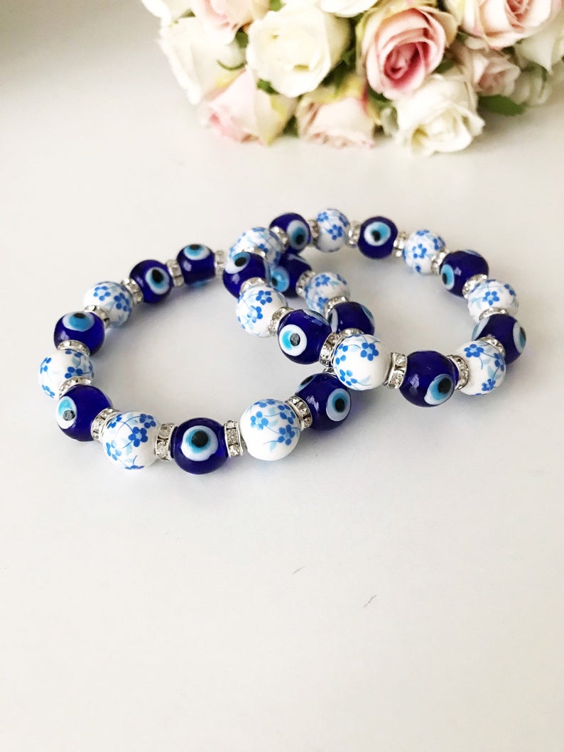 A beautiful Glass Evil Eye Bracelet featuring ceramic and blue glass beads, showcasing a vibrant blue evil eye charm.