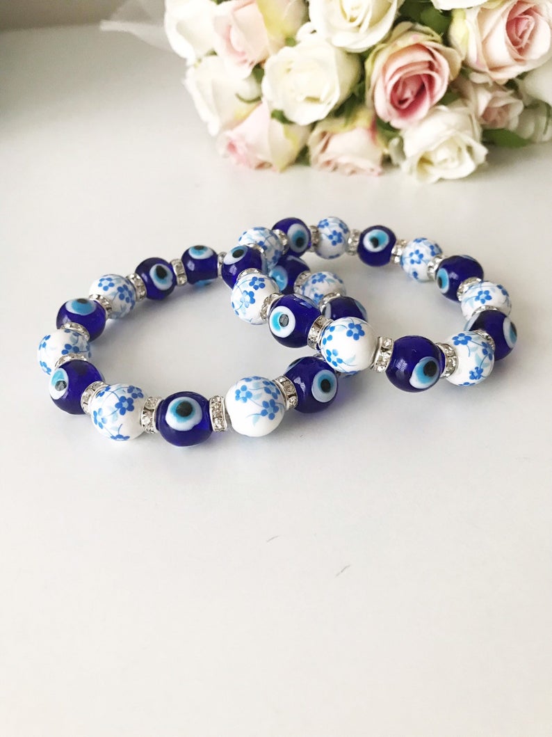 A beautiful Glass Evil Eye Bracelet featuring ceramic and blue glass beads, showcasing a vibrant blue evil eye charm.