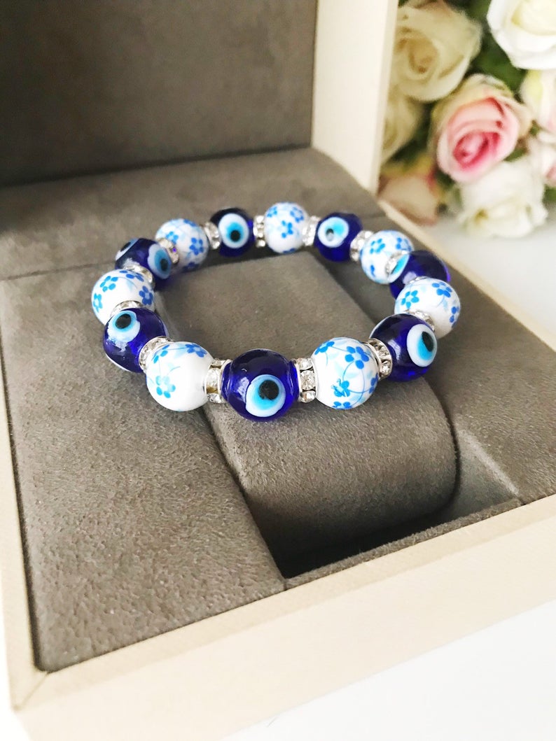 A beautiful Glass Evil Eye Bracelet featuring ceramic and blue glass beads, showcasing a vibrant blue evil eye charm.