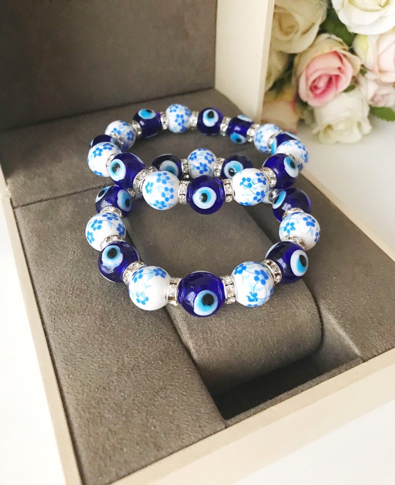 A beautiful Glass Evil Eye Bracelet featuring ceramic and blue glass beads, showcasing a vibrant blue evil eye charm.