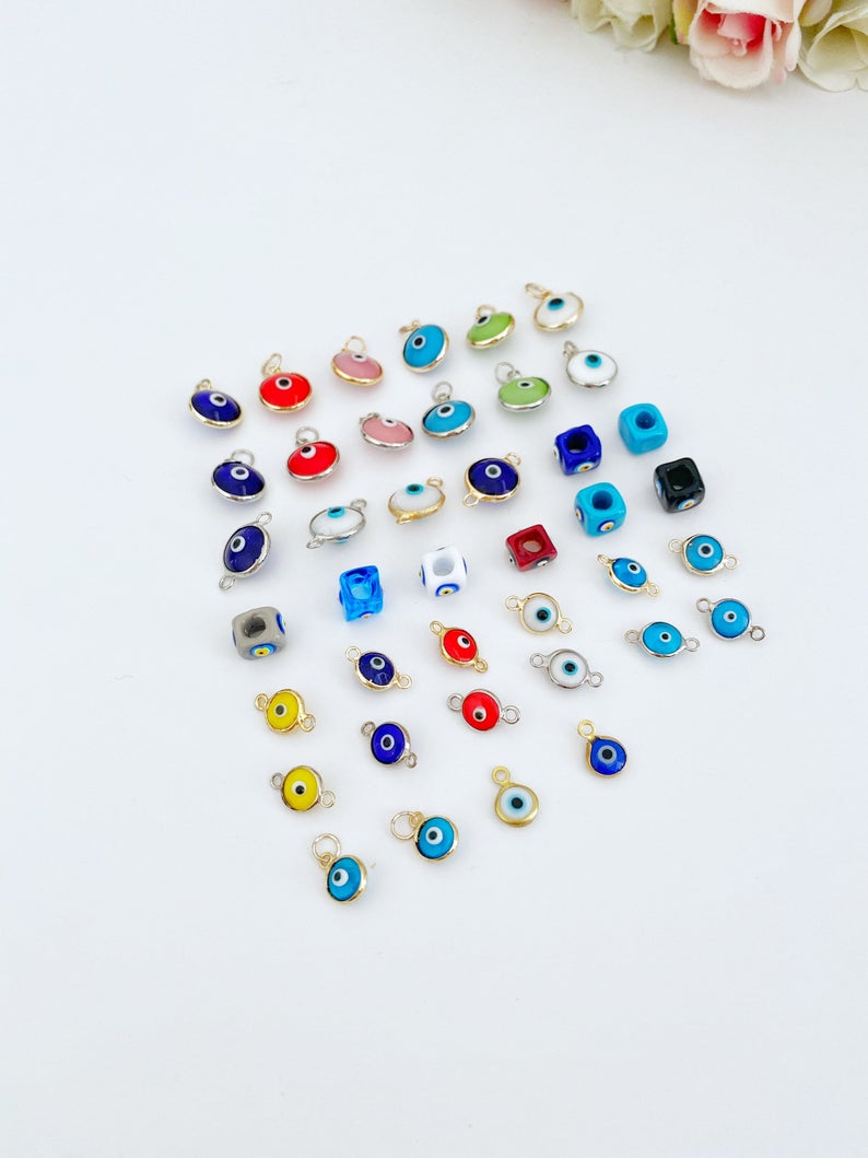 A collection of 5 Glass Evil Eye Charms made from Murano glass, showcasing various designs and vibrant colors, perfect for DIY jewelry making.