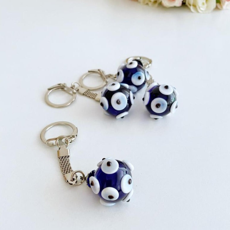 A beautiful Glass Evil Eye Keychain featuring a blue glass bead, symbolizing protection and luck, attached to a silver keyring.