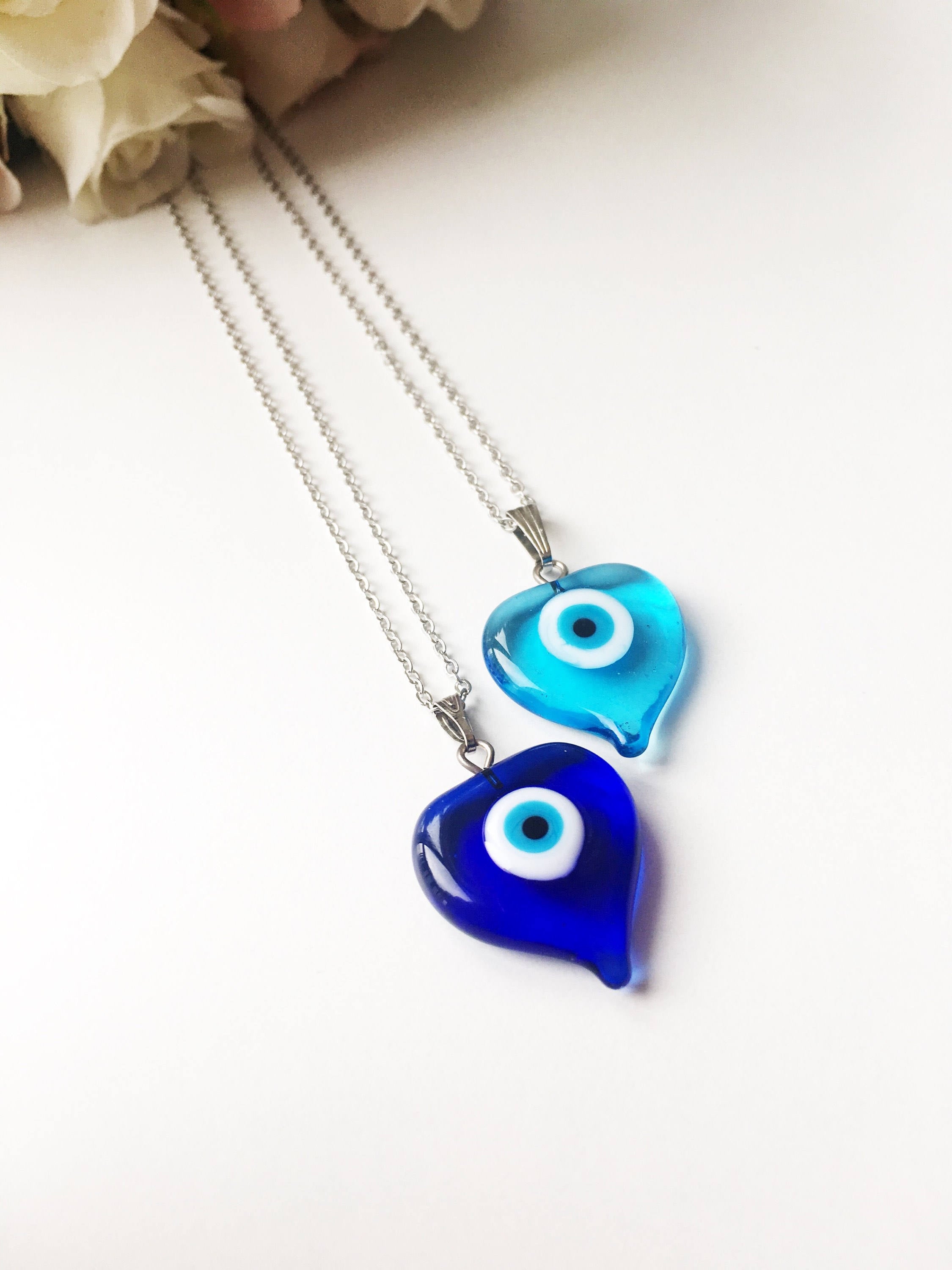 A beautiful Glass Evil Eye Necklace featuring a blue evil eye bead on a stainless steel chain, available in round, heart, and oval shapes.