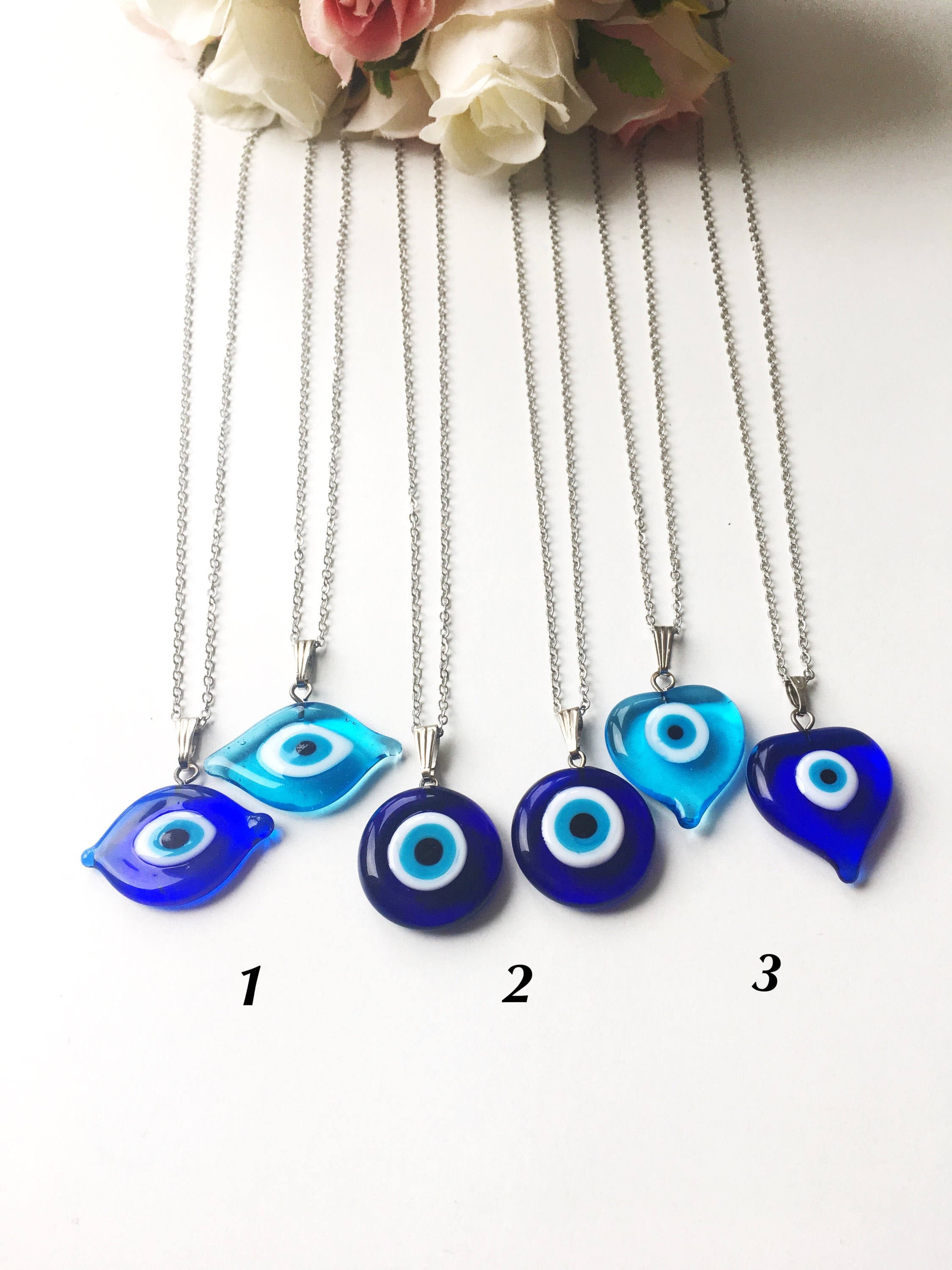 A beautiful Glass Evil Eye Necklace featuring a blue evil eye bead on a stainless steel chain, available in round, heart, and oval shapes.