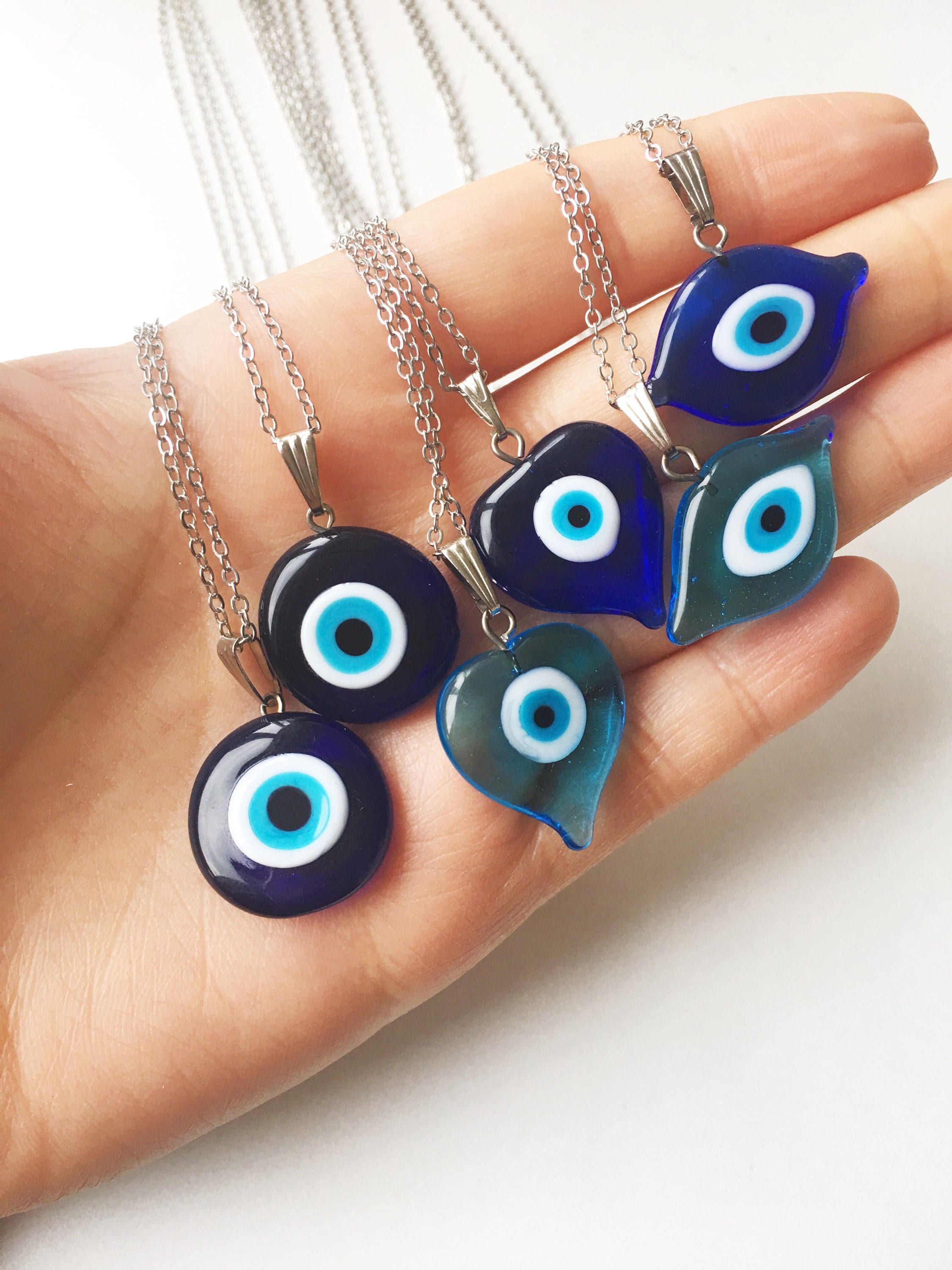 A beautiful Glass Evil Eye Necklace featuring a blue evil eye bead on a stainless steel chain, available in round, heart, and oval shapes.