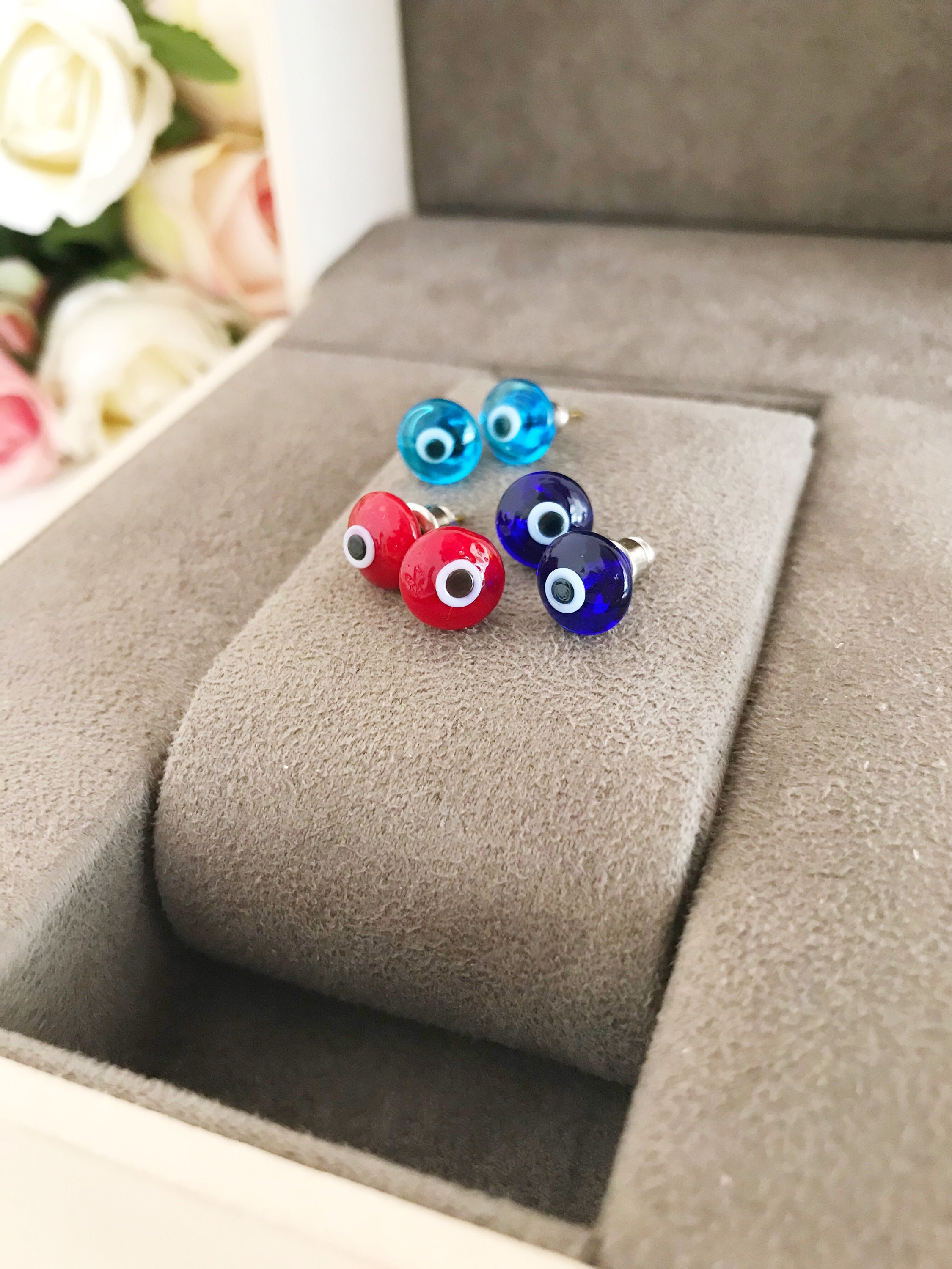 A pair of handmade glass evil eye stud earrings in various vibrant colors, symbolizing protection and good fortune.