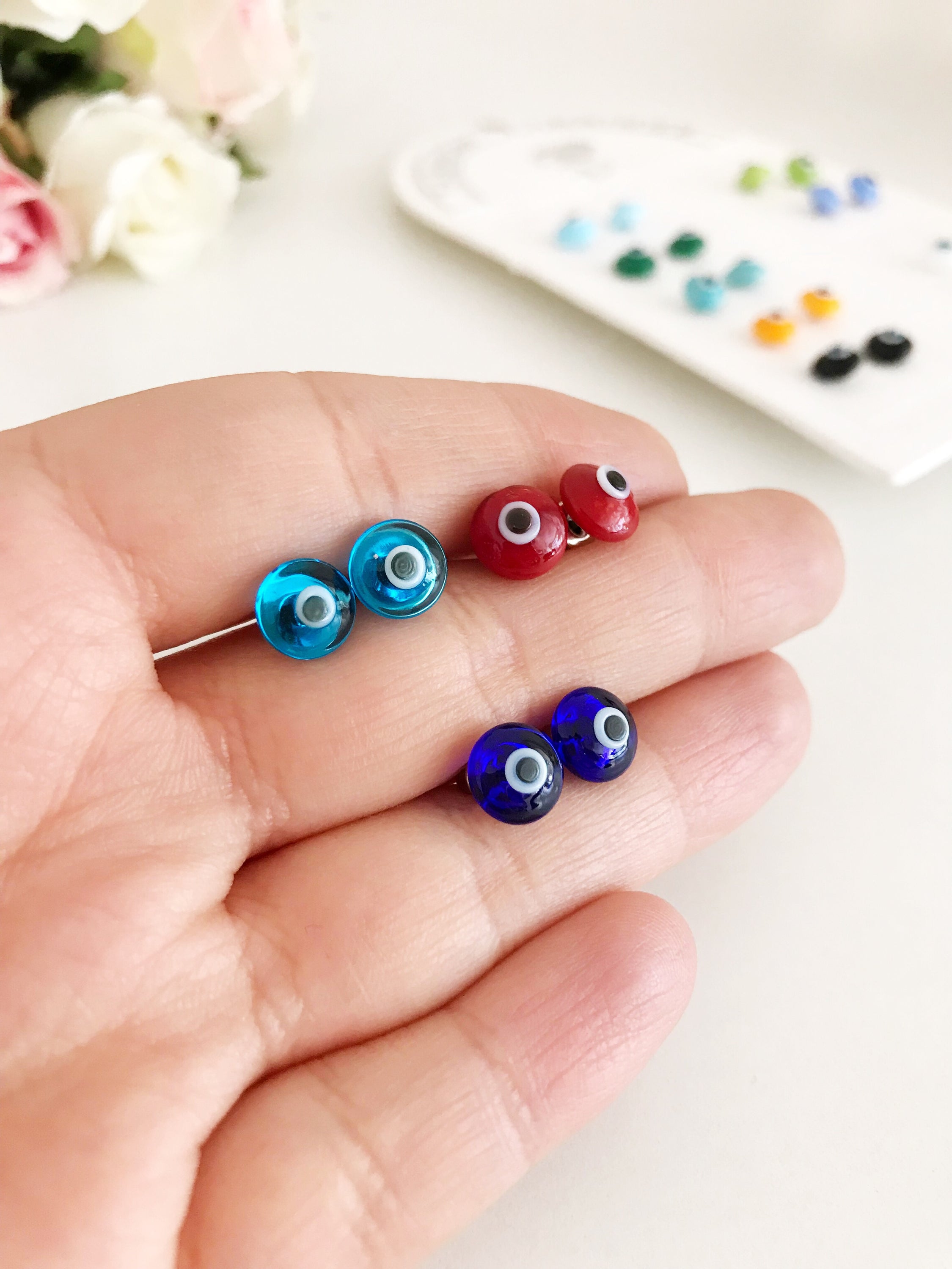 A pair of handmade glass evil eye stud earrings in various vibrant colors, symbolizing protection and good fortune.