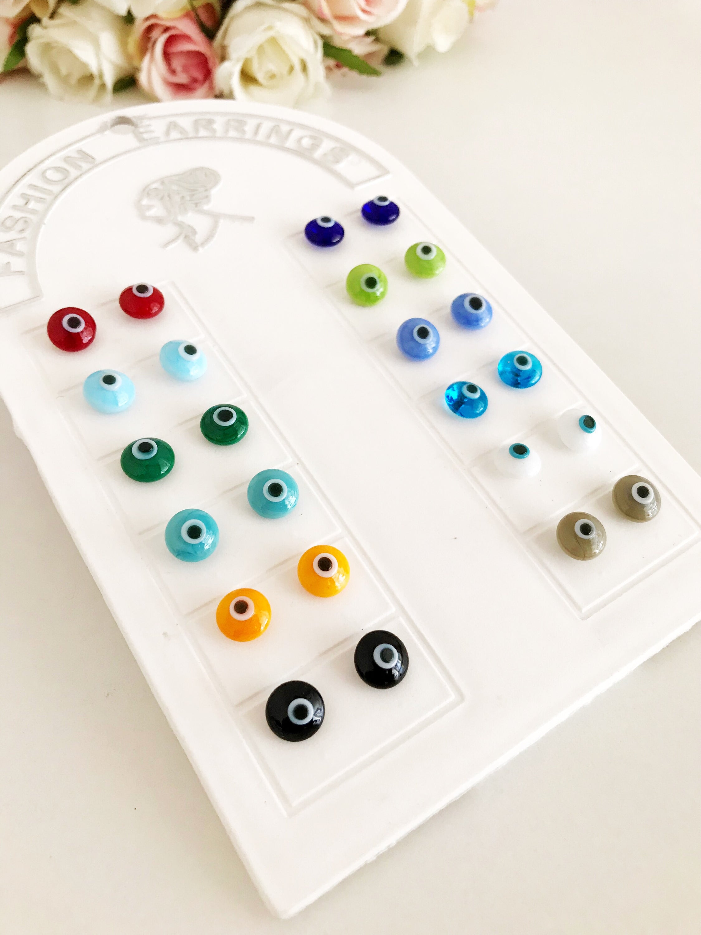 A pair of handmade glass evil eye stud earrings in various vibrant colors, symbolizing protection and good fortune.