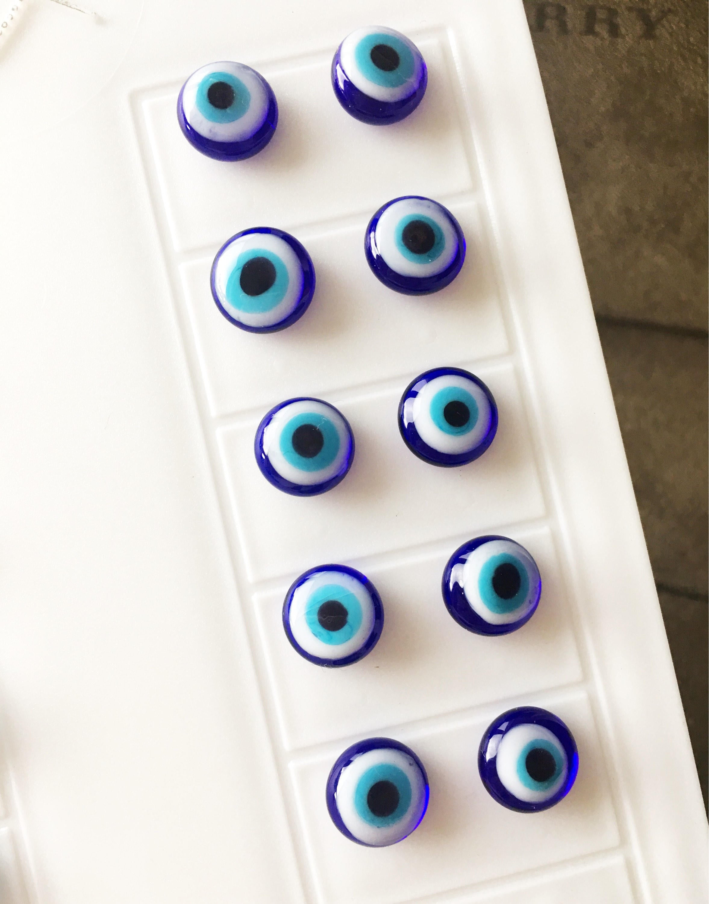 A pair of handmade glass evil eye stud earrings in dark blue and turquoise, featuring a protective eye design set in stainless steel.