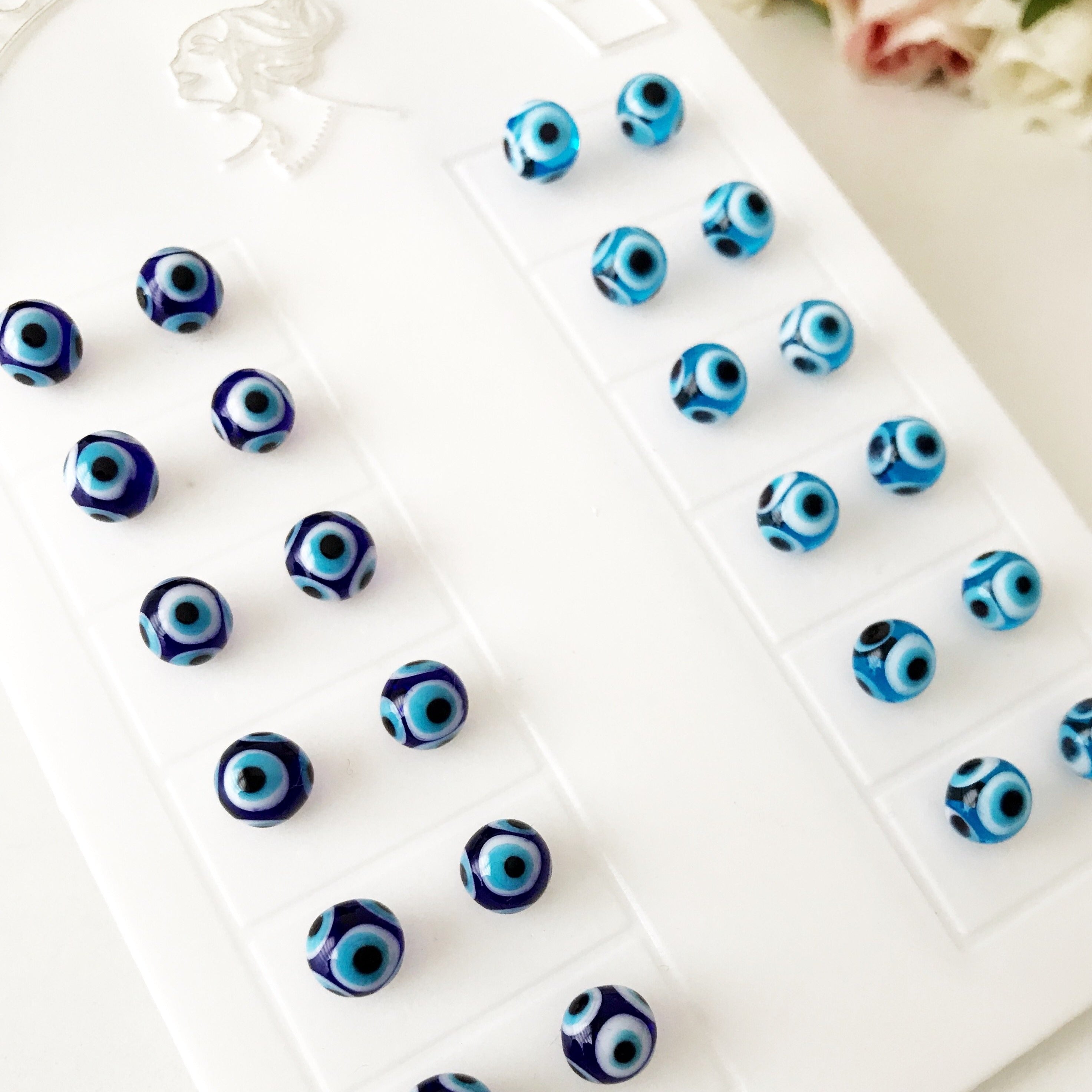 A pair of handmade glass evil eye stud earrings in dark blue and turquoise, symbolizing protection and good luck, displayed elegantly.