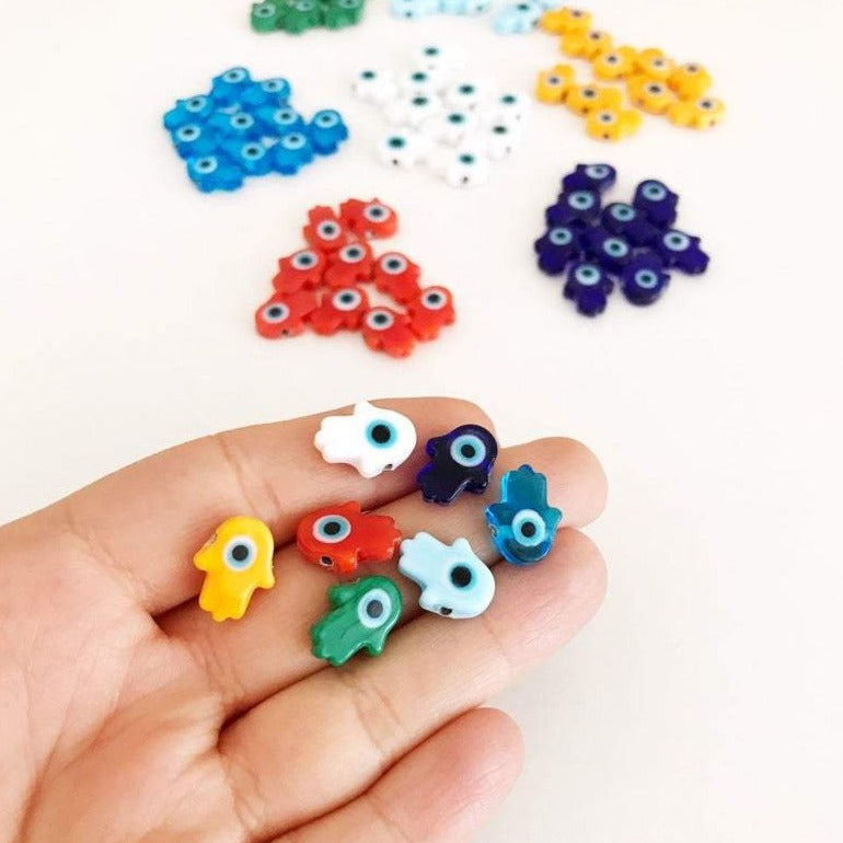 A collection of 10 handmade glass hamsa evil eye spacer beads in various colors, showcasing their intricate designs and craftsmanship.