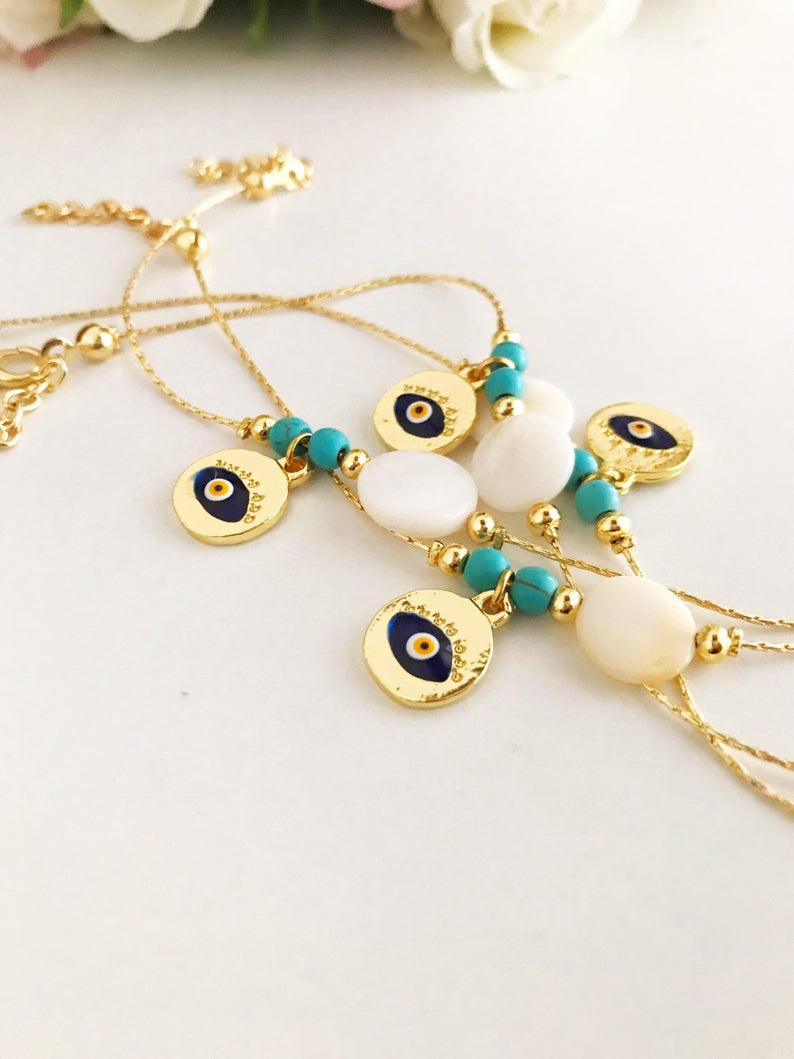 Gold Chain Evil Eye Bracelet featuring a gold evil eye charm and mother of pearl charm, elegantly designed with an adjustable length.