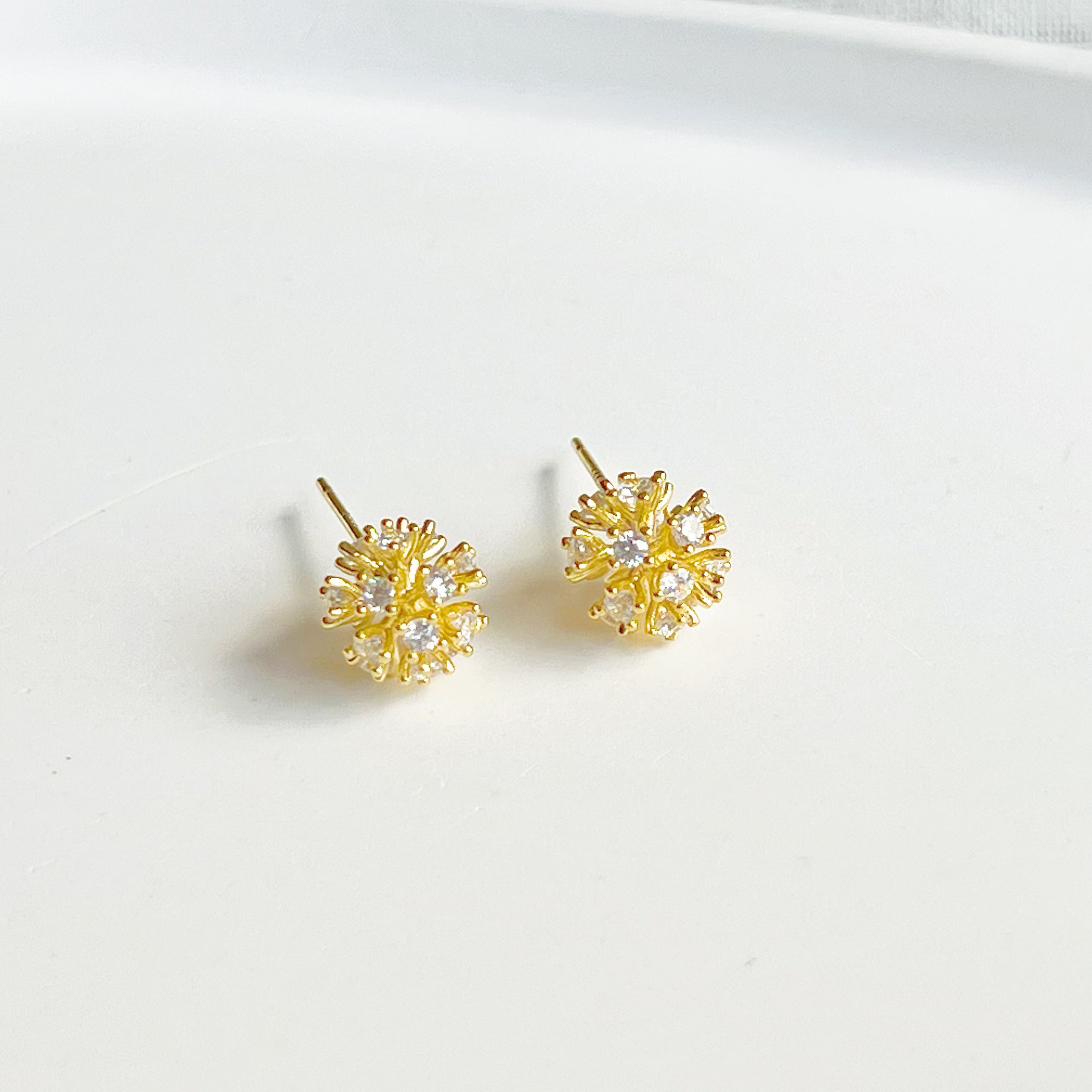 A pair of elegant gold crystal dandelion stud earrings featuring clear zircons, symbolizing hope and love.