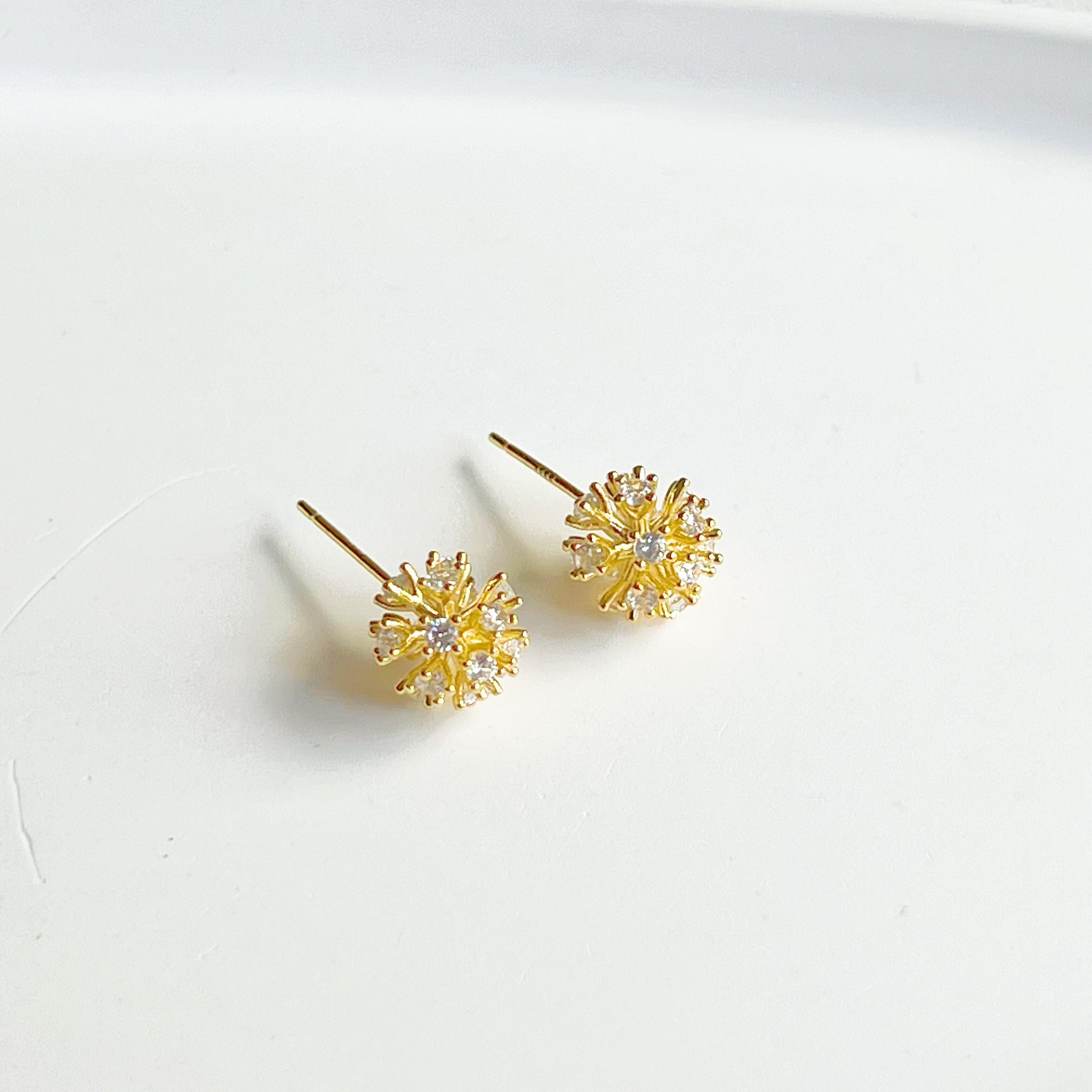 A pair of elegant gold crystal dandelion stud earrings featuring clear zircons, symbolizing hope and love.