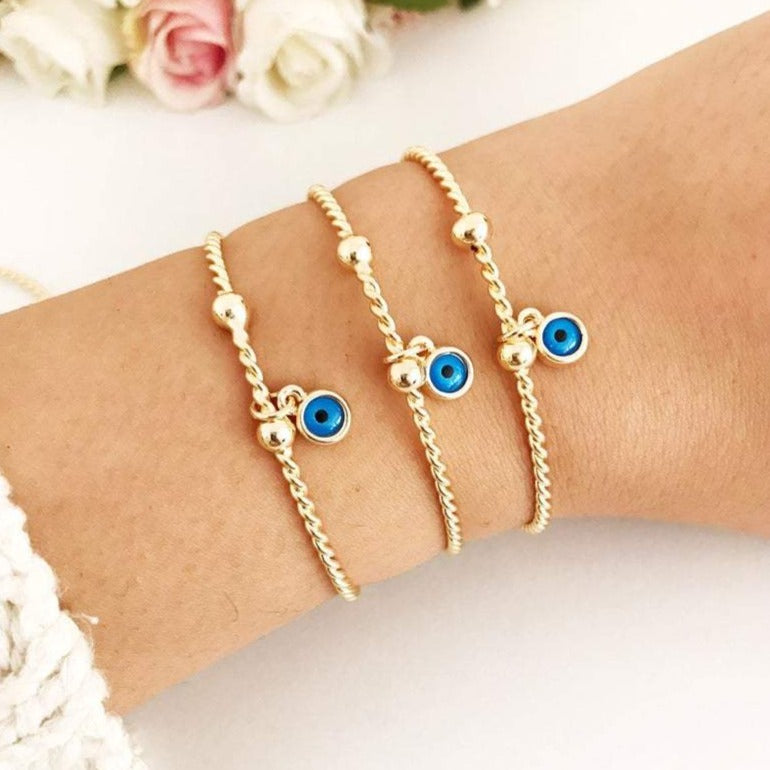 Gold Evil Eye Bangle Bracelet featuring a movable blue evil eye charm, crafted from tarnish-resistant stainless steel.