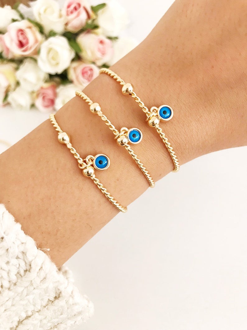 Gold Evil Eye Bangle Bracelet featuring a movable blue evil eye charm, crafted from tarnish-resistant stainless steel.